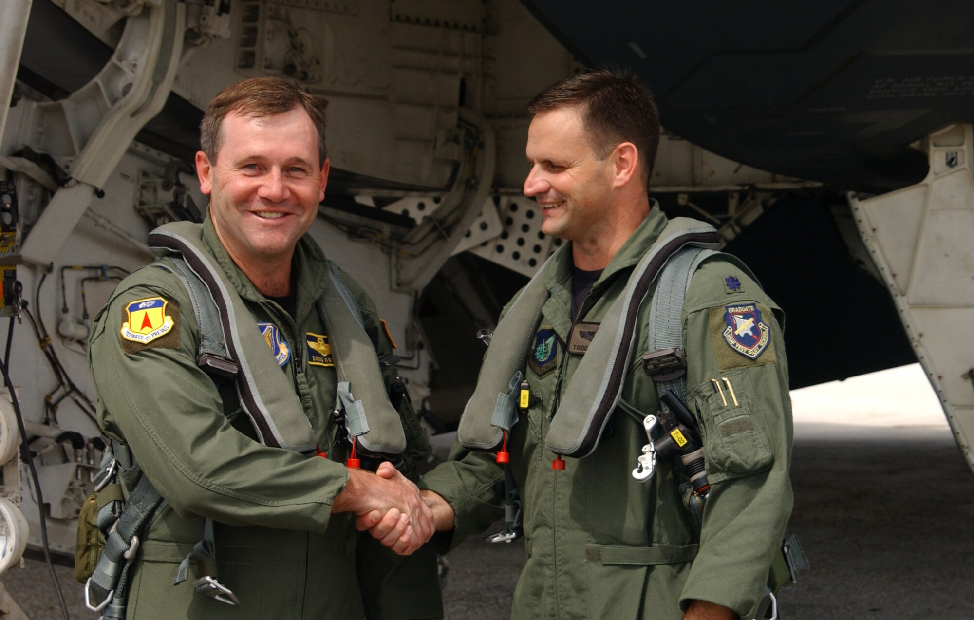 Lt. Col Todd Copeland, 393rd Expeditionary Bomb Squadron director of operations (right) shakes hands with Brig. Gen. Douglas Owens in front of the stealth bomber before their flight. The B-2 Spirit has a crew of two pilots, a pilot in the left seat and mission commander in the right, compared to the B-1B's crew of four and the B-52's crew of five. Both aviators have the ability to fly the jet during a sortie. (Air Force photo/Tech. Sgt. Steven Wilson)

