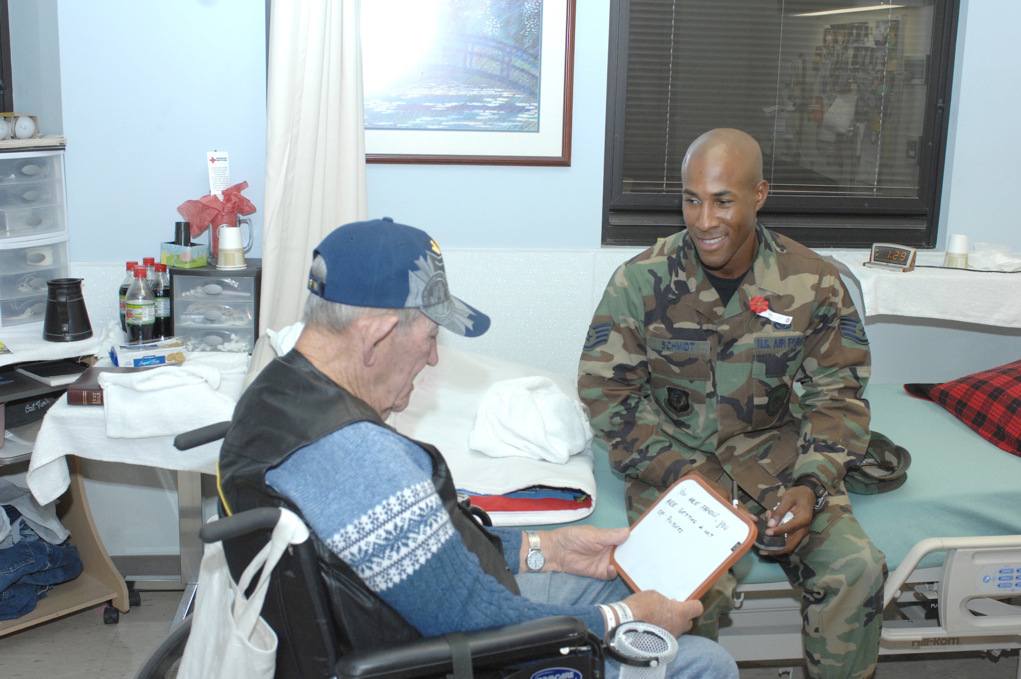 CANNON AIR FORCE BASE, N.M. -- Staff Sgt. Eric Schmidt, 27th Special Operations Civil Engineer Squadron, spends time with World War II veteran Audrey Down at the Veterans Administration Hospital in Amarillo, Texas. Mr. Down, who is deaf, used a white board and a marker to communicate. Sergeant Schmidt was one of 32 Cannon Airman who traveled to the hospital on Nov. 9 as part of Cannon's Middle Tier organization's community service program. (Air Force photo by Greg Allen)