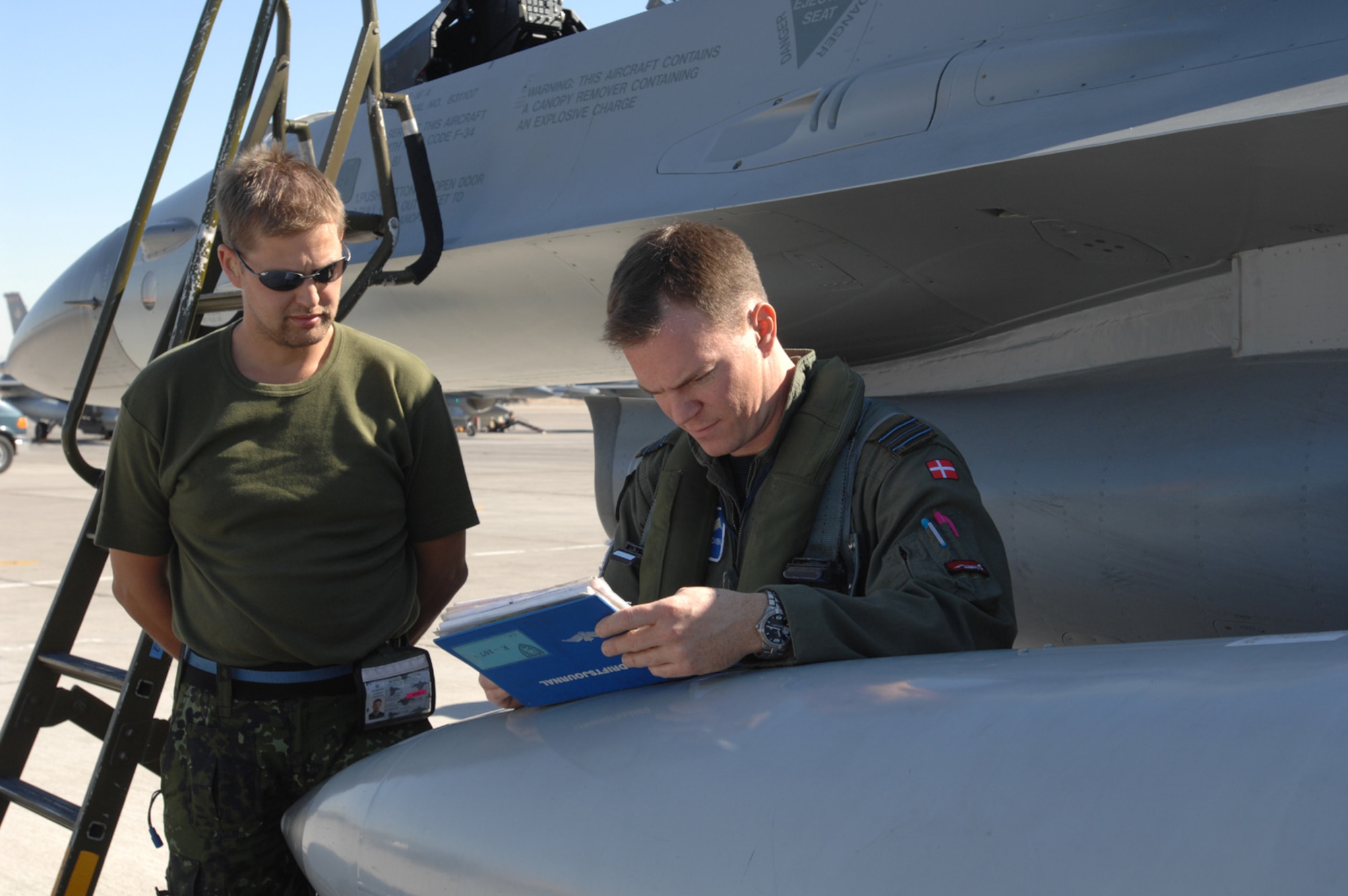 Danish air force Capt. Eric Scharnowski reviews the preflight checklist as Lance Cpl. Stig Clausen waits for instructions prior to a Red Flag sortie. Red Flag tests aircrews’ war-fighting skills in realistic combat situations. (USAF photo by Staff Sgt. Kenny Kennemer)