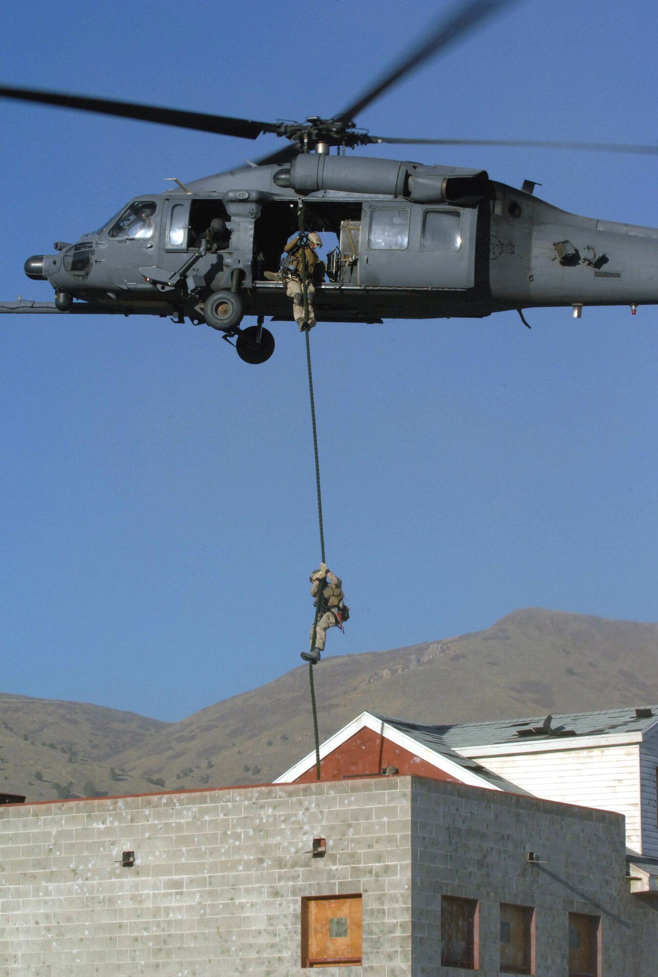 Pararescuemen fast rope into an urban training village for an extraction of a simulated downed pilot during a combat search and rescue integration exercise Nov. 8 at Camp Williams, Utah. The pararescuemen are from the 58th Rescue Squadron, Nellis Air Force Base, Nev. Members of the 34th Weapons Squadron from Nellis AFB led the search and recovery training. The exercise expanded the integration with Utah's 211th Aviation Group AH-64 Apache Joint Rotary Wing, 4th Fighter Squadron F-16 Fighting Falcon assets from Hill AFB, Utah, and special operations forces. Exercise participants also conducted extensive joint combat search and rescue operations against surface-to-air threats. The exercise is being run held Nov. 6 through 15. (U.S. Air Force photo/Master Sgt. Kevin J. Gruenwald) 
