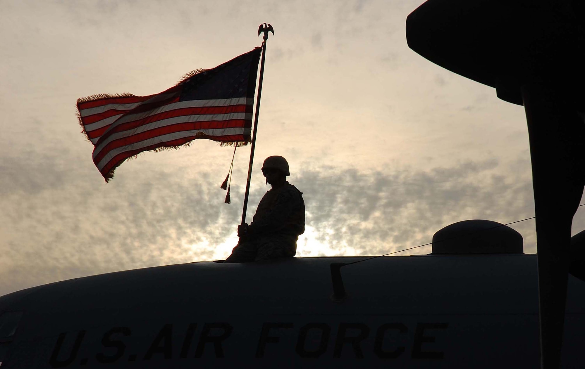 SOUTHWEST ASIA -- Master Sgt. Roger Richardson, 386th Expeditionary Aircraft Maintenance Squadron flying crew chief, proudly holds an American flag atop a C-130 aircraft, tail number 63-7865, from Ramstein AB, Germany, at an undisclosed location in Southwest Asia Nov. 13. The aircraft had just flown its last combat mission and will be flown to Davis-Monthan AFB, Ariz., where it will be laid to rest at the "boneyard." The C-130 became an honorary purple heart recipient in June of 1972 for damages sustained from mortar fire in Vietnam.  (U.S. Air Force photo/Staff Sgt. Tia Schroeder)
