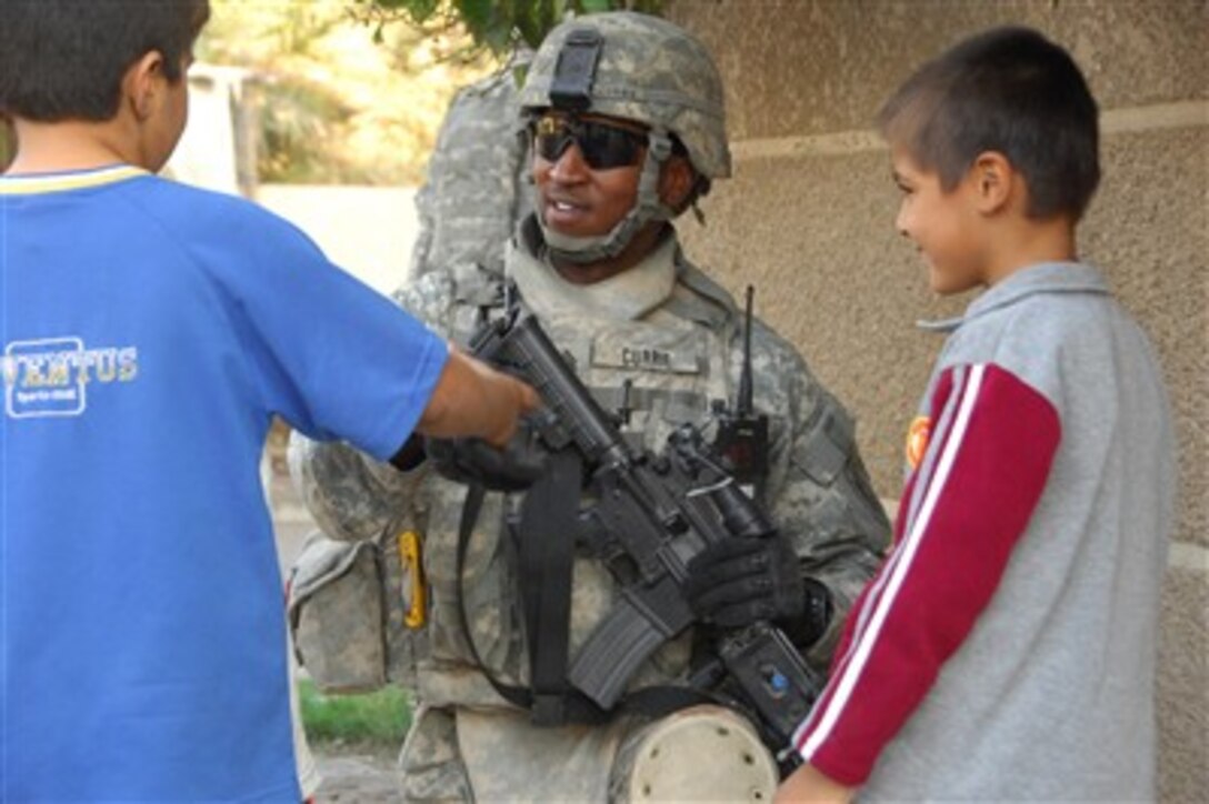 Army Staff Sgt. Christopher Currie talks with two Iraqi boys during a patrol in the Hateem neighborhood of Baghdad, Iraq, on Nov. 9, 2007.  Currie is from Alpha Battery, 2nd Battalion, 32nd Field Artillery Regiment and is attached to the 2nd Brigade Combat Team, 1st Cavalry Division.  