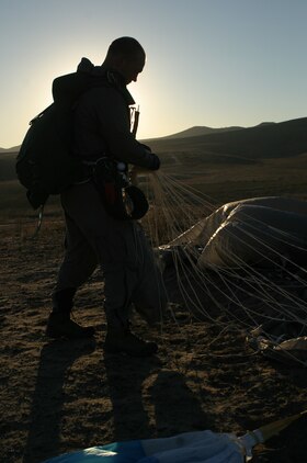 A Marine from U.S. Marine Corps Forces, Special Operations Command's 1st Marine Special Operations Battalion, gathers his parachute as the sun sets at Basilone Drop Zone here Nov. 14. Marines conducted static-line and free-fall jumps during the day and night in order to hone their parachute insertion skills.