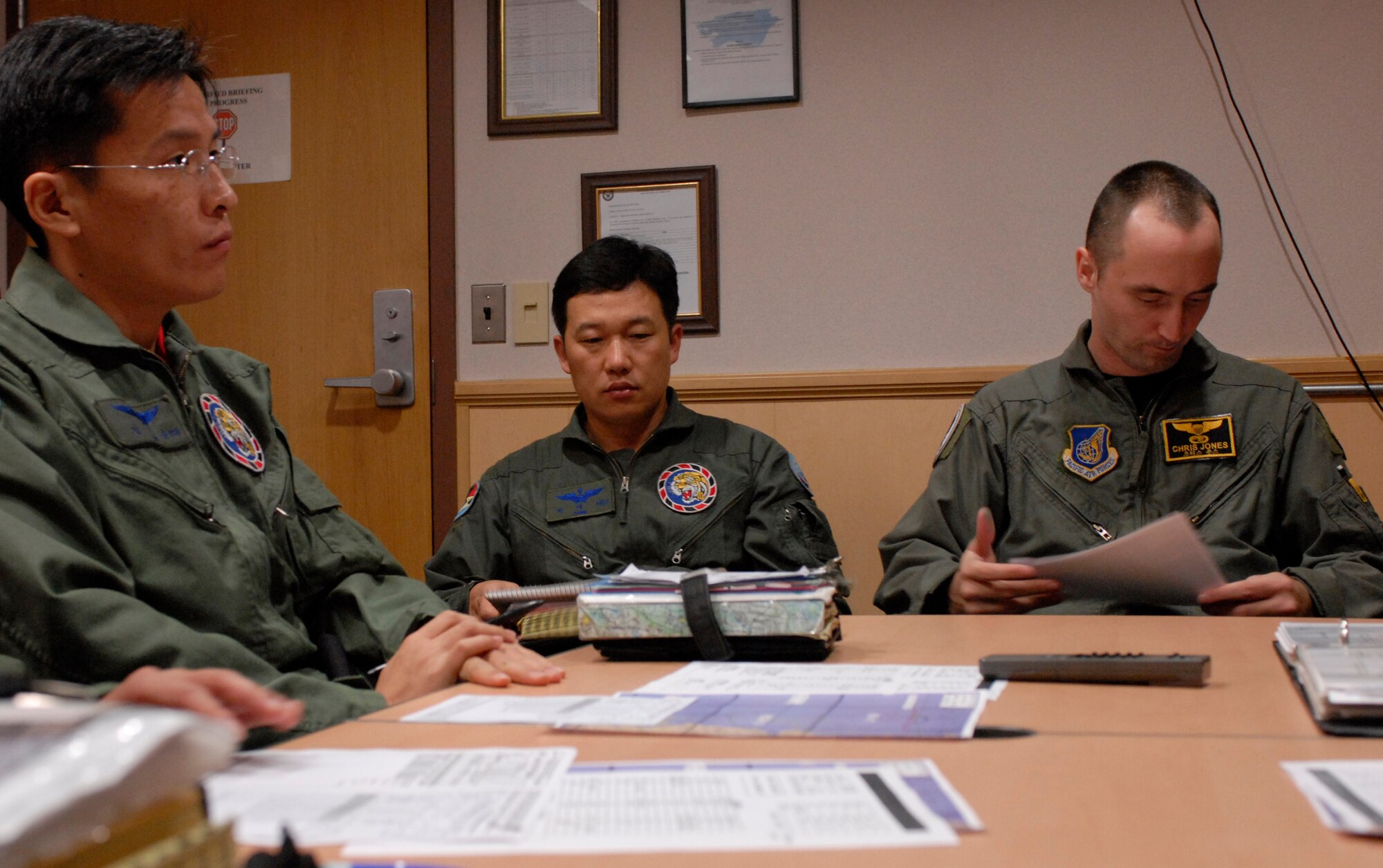 KUNSAN AIR BASE, South Korea--  Capt. Yim, Chang-soon weapons officer and Maj. Park, Dae-seo, director of operations from the 111th Fighter Squadron and Capt. Christopher Jones, 80th Fighter Squadron pilot, prepares for a flight mission brief here Nov. 14. ROKAF pilots and Wolf Pack pilots trained together on a joint mission to give pilots from both countries a chance to work together and hone their war-fighting skills.  (U.S. Air Force Photo/Staff Sgt. Araceli Alarcon) 