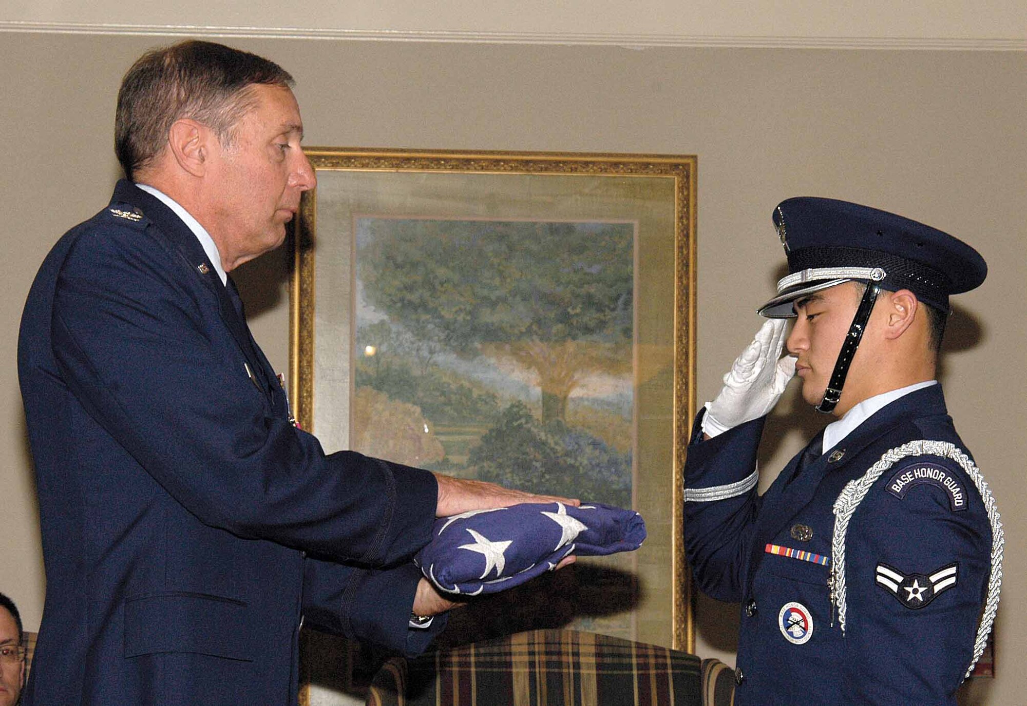 Tinker Honor Guard member Airman 1st Class Christian Sousa presents a flag to Col. James Hall during his Nov. 8 retirement after 30 years of service. (Air Force photo by Margo Wright)