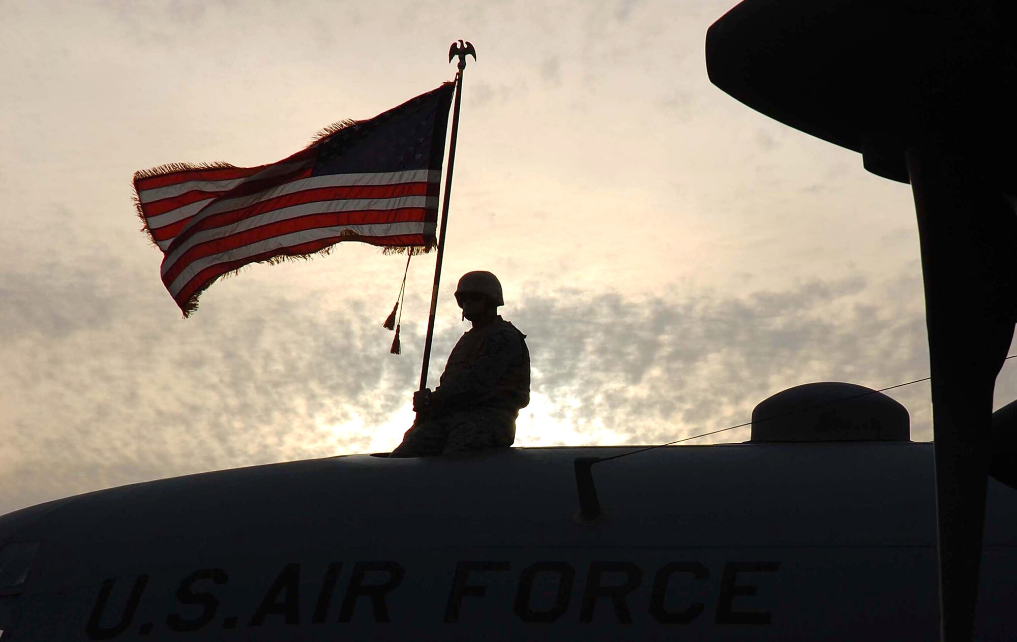 Master Sgt. Roger Richardson holds an American flag atop a C-130 Hercules, tail number 63-7865, Nov. 13 in Southwest Asia. The aircraft from Ramstein Air Base, Germany, had just flown its last combat mission and will be flown to Davis-Monthan Air Force Base, Ariz., where it will be laid to rest at the "boneyard." Sergeant Richardson is a 386th Expeditionary Aircraft Maintenance Squadron flying crew chief. (U.S. Air Force photo/Staff Sgt. Tia Schroeder) 
