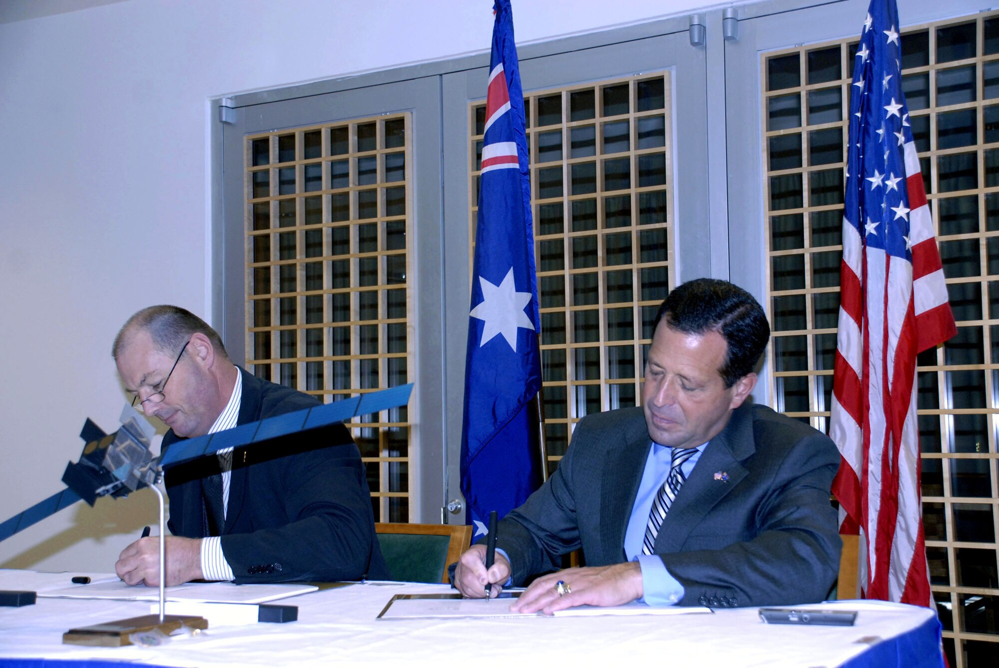 Bruce Lemkin (right), deputy undersecretary of the Air Force for international affairs, and Mark Reynolds, Royal Australian Air Force Counsellor Defence Material, sign a memorandum of agreement at the Australian Embassy in Washington D.C. Nov. 14 that will provide both nations assured access to the new wideband global satellite system. The new six-satellite system is the next generation in communications satellites and is better able to handle bandwidth-intensive applications such as video streaming, teleconferencing, real-time data transmission, and high-resolution imaging. (U. S. Air Force photo/Staff Sgt. J.G. Buzanowski)
