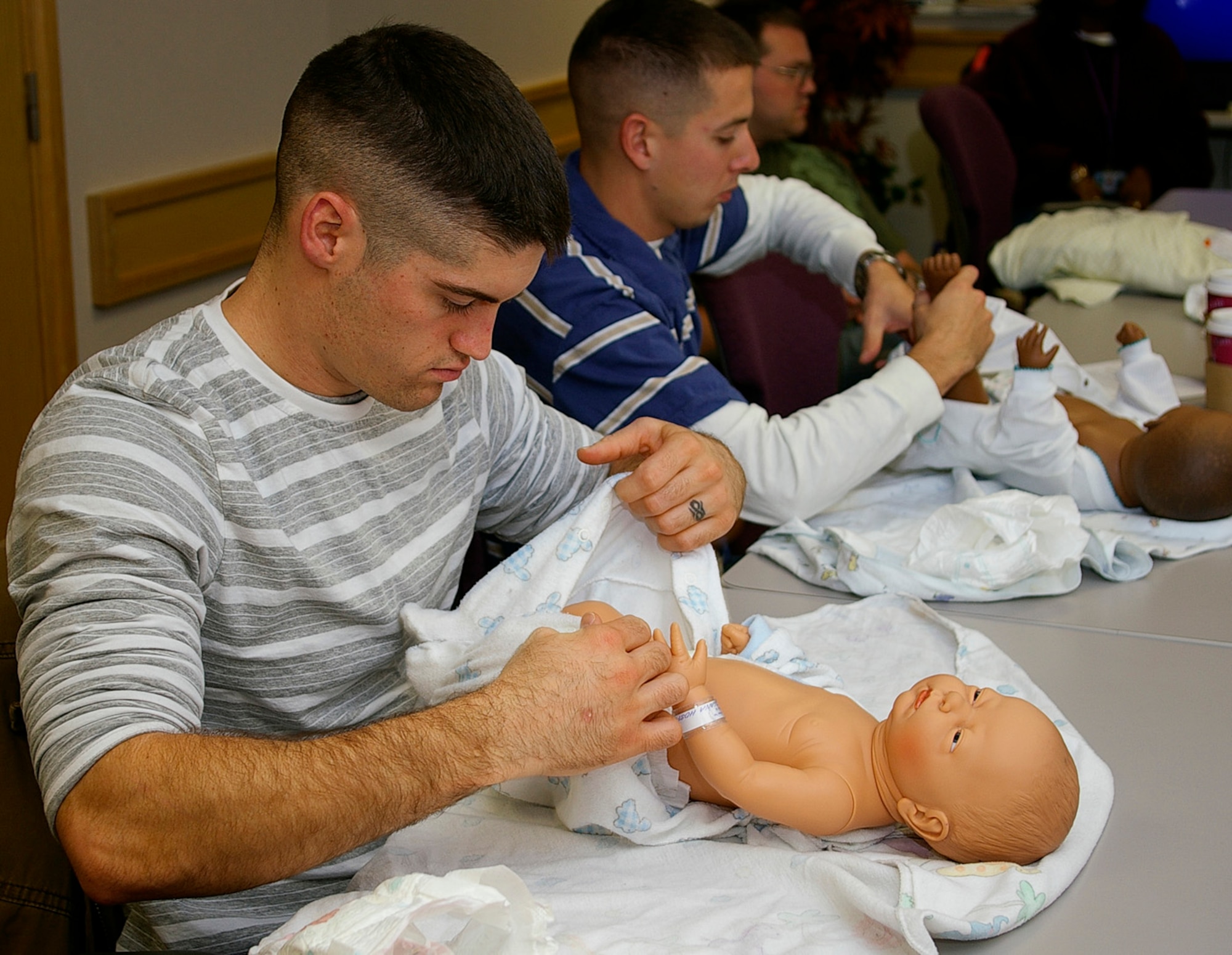 Senior Airman Joshua Haynes,left, 48th Component Maintenance Squadron, RAF Lakenheath, and Senior Airman Patrick Gooding, 48th Aircraft Maintenance Squadron, RAF Lakenheath, practice putting a diaper on a "baby" at the Dads Class at 48th Medical Operations Squadron Family Advocacy Oct. 26. The class, for men only, is instructed by an experienced father and topics include bringing baby home from hospital, changing diapers, and breastfeeding. (U.S. Air Force photo by Karen Abeyasekere)