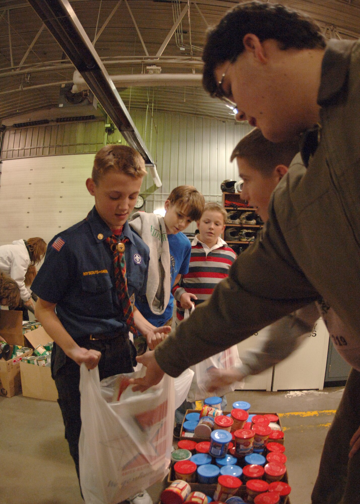 Patrick Sprague hands out cake mix to the assembly line of baggers during Operation Warm Heart here Nov. 13. The Boy Scouts, Cub Scouts, Girl Scouts and first sergeants helped sort thousands of canned goods and assembled 125 bagged meals during the event. (U.S. Air Force photo/Senior Airman Chad Kellum)
