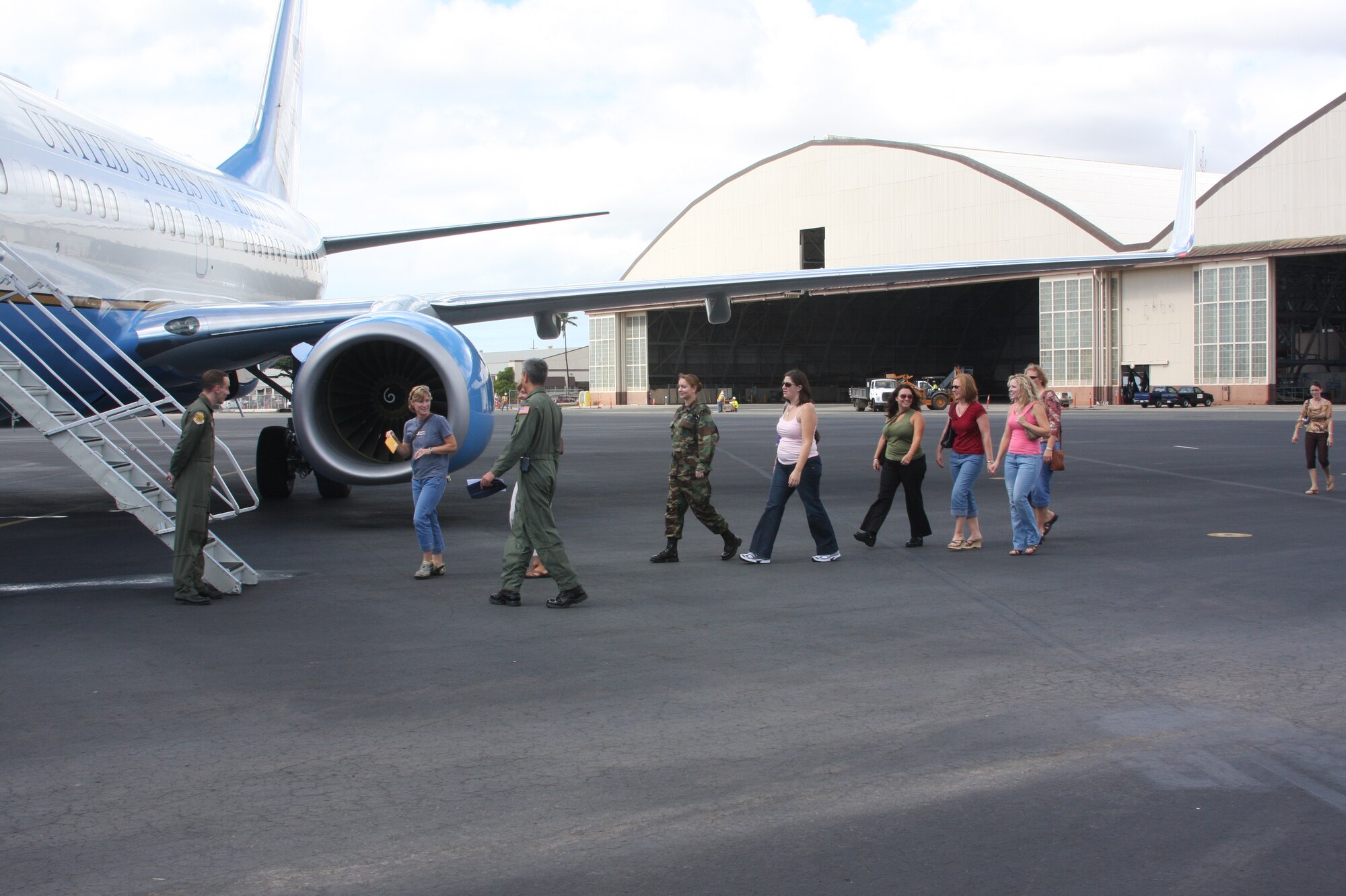 Tech. Sgt. Adam Giddings, 65th Airlift Squadron, welcomes squadron spouses aboard the aircraft for a spouse's familiarization flight. During the flight over the Hawaiian islands, the spouses received a meal and opportunities to check out the aircraft. Photo by Tech. Sgt. Sean Broderick.