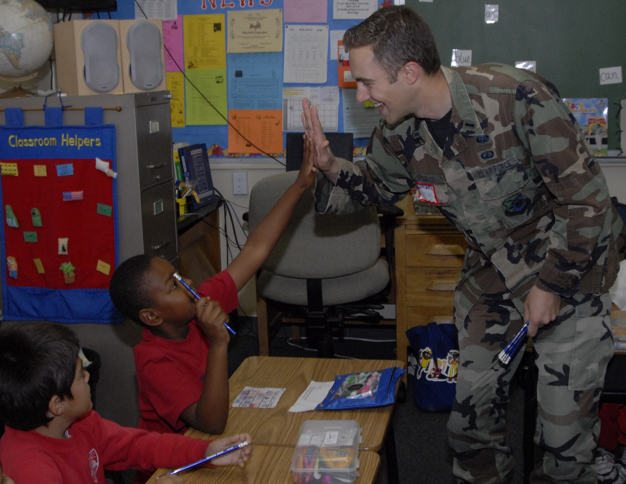 Lt. James Spindler, Satellite Control and Network Group, gives a student at St. Jerome’s Catholic School in Westchester a high five. Approximately 20 military members, including ten Air Force personnel, spoke to students about their military career and the importance of education. The service members were recognized as a group at a school assembly. (Photo by Joe Juarez)
