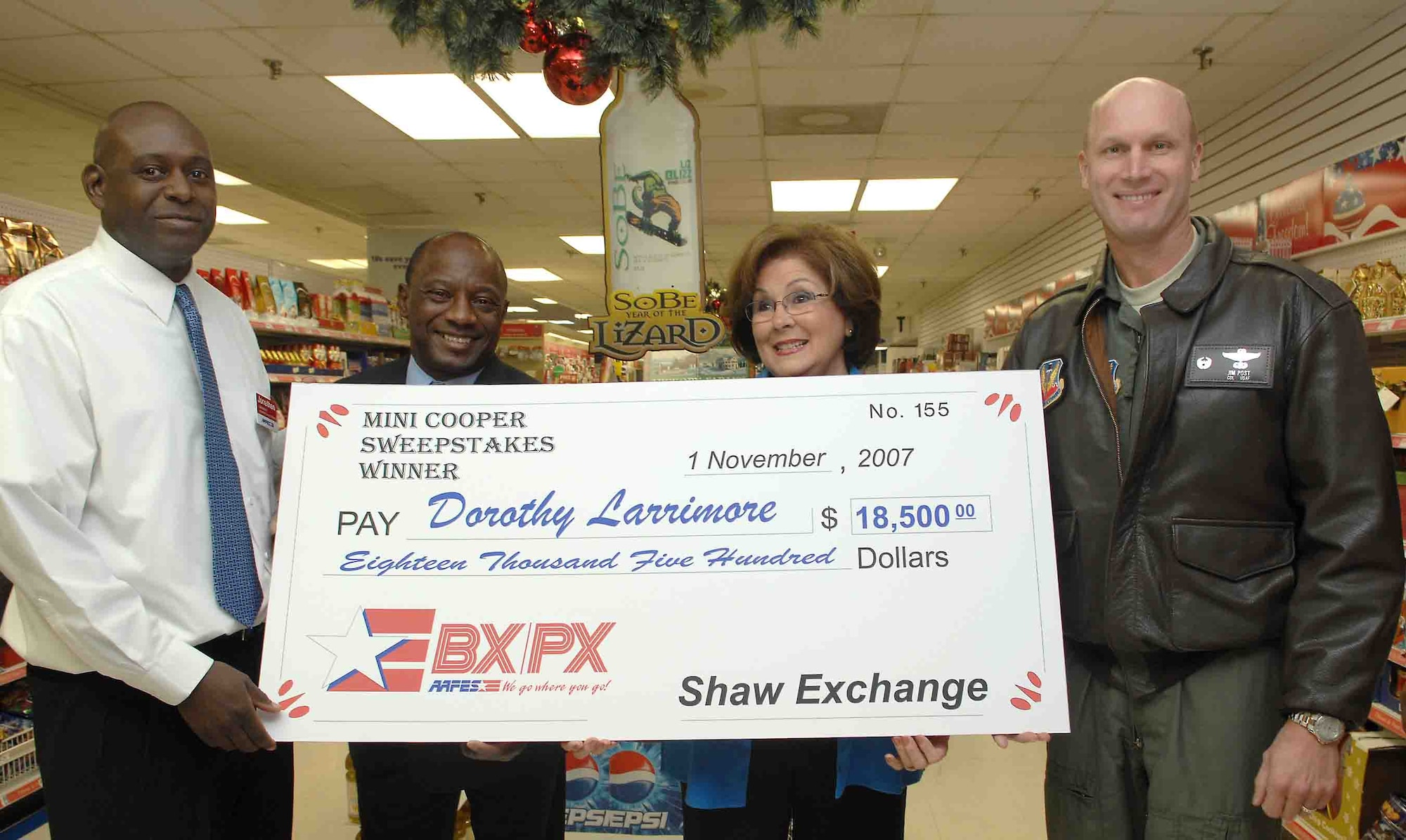 SHAW AIR FORCE BASE, S.C. -- Jonathan Bright, Army Air Force Exchange Service store manager, Maurice Joiner, AAFES general manager, and Col. James Post, 20th Fighter Wing commander, present a check for $18,500 to Mrs. Dorothy Larrimore Nov 16. Mrs. Larrimore won the Sobe Mini Cooper Sweepstakes sponsored by Pepsi Cola and AAFES. (U.S. Air Force photo/Airman 1st Class William Coleman)