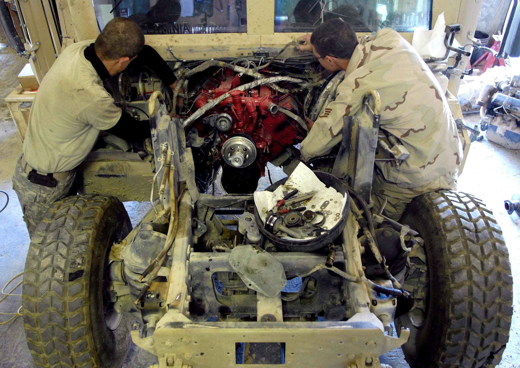 Tech. Sgt. James Nelson and Staff Sgt. Logan Pike work on the wiring harness of a Humvee Nov. 1 at forward operating base Lagman, Afghanistan. Sergeants Nelson and Pike are filling 365-day Army 'in-lieu-of' taskings.  Sergeant Nelson is deployed from Nellis Air Force Base, Nev., while Sergeant Pike is deployed from Malmstrom AFB, Mont. (U.S. Air Force photo/Staff Sgt. Brian Ferguson)