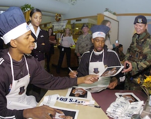 Rookie Guard Nick Young and Forward Dominic McGuire sign photographs for servicemembers at the Freedom Hall Dining Facility after serving dinner on Nov. 13. (US Air Force/Bobby Jones)