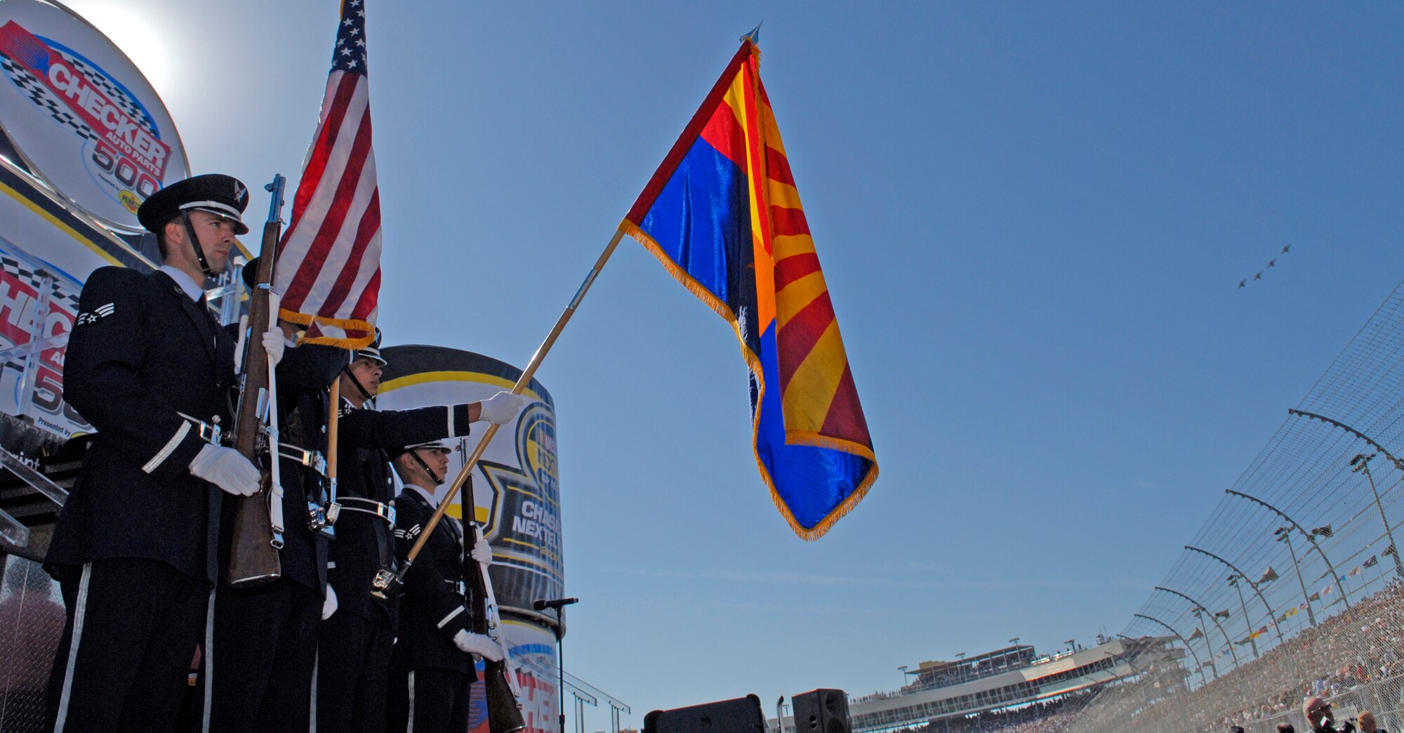 FROM LEFT: Senior Airman Ryan Vogt, Airmen 1st Class Thomas Clonts and Julio Armijos, and Senior Airman Homer Valdez, members of the Luke Air Force Base Honor Guard, present the colors during the opening ceremony at the Nov. 11 NASCAR Checker Auto Parts 500 at Phoenix International Raceway. Jets from the 61st Fighter Squadron also perform a formation flyover. (photo by Master Sgt. William Gomez)