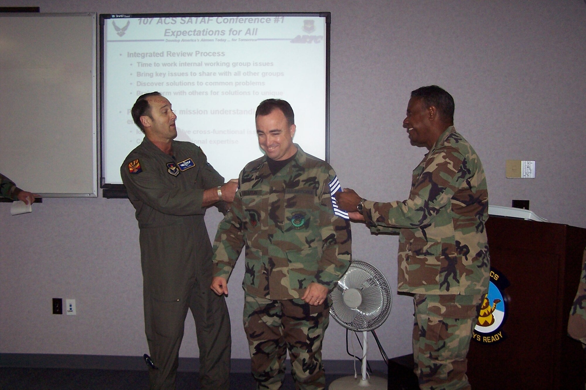 Brig. Gen. Tom Jones, 56th Fighter Wing commander, left, and Lt. Col. Todd Scott, 607th Air Control Squadron commander, right, gives Senior Master Sgt. Donald Staflin, 607th ACS, a traditional slug honoring his selection to chief Nov. 15. (photo by Staff Sgt. Jamesia Nichols)