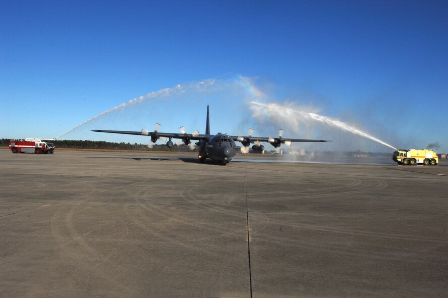 An AC-130H gunship piloted by Lt. Gen. Michael Wooley, Air Force Special Operations Command commander, rolls under a water arch provided by the 1st Special Operations Civil Engineer Squadron fire and emergency services flight, after landing at Hurlburt Field Nov.15. This was the general's finis, or final, flight before he relinquishes command of AFSOC Nov. 27. General Wooley will retire later this year after 35 years of service. (U.S. Air Force Photo/Senior Airman Stephanie Jacobs)
