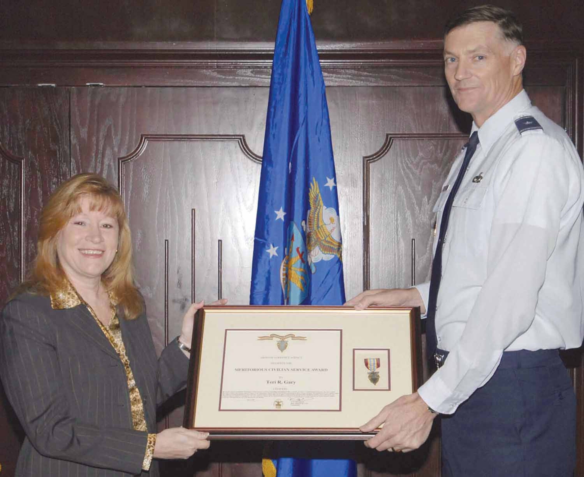 Brig. Gen. Andrew E. Busch, Defense Supply Center Richmond commander, presents Teri R. Gary with the Meritorious Civilian Service Award Nov. 7 for her innovative initiatives in integrating Defense Logistics Agency business practices into the newly designed, lean production processes as a transformation liaison officer with the DLA forward presence team assigned to Tinker. (Air Force photo by Kelly White)