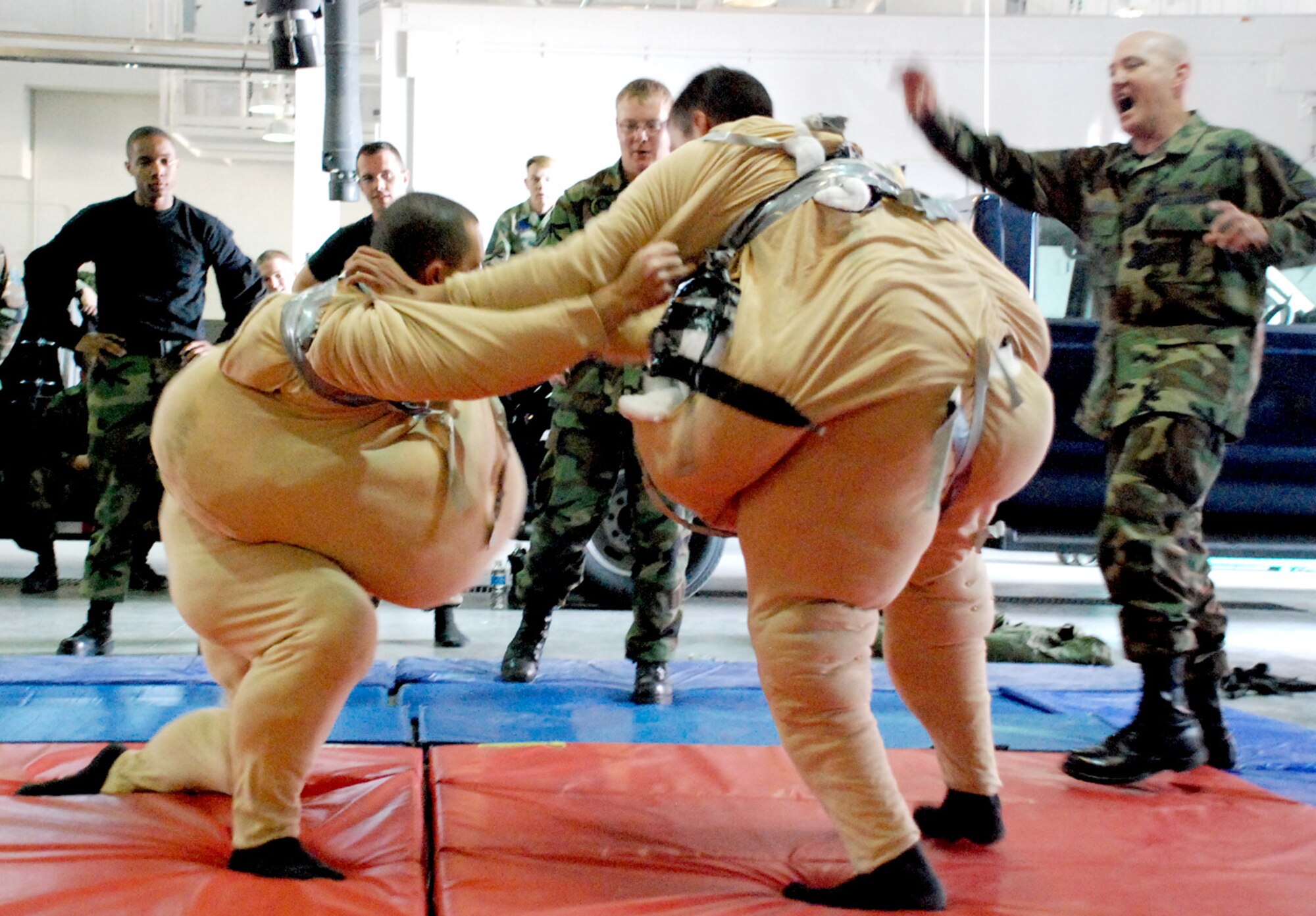 First Lt. Charles Doyle, 90th Maintenance Group, and 2nd Lt. James Gutierrez, 90th Missile Maintenance Squadron, don sumo regalia and attemp to wrestle each other to the floor. Master Sgt. Joseph Gaddis refereed the battle that took place in a maintenance bay at Bldg. 1235 Nov. 9 (Photo by Airman 1st Class Daryl Knee).