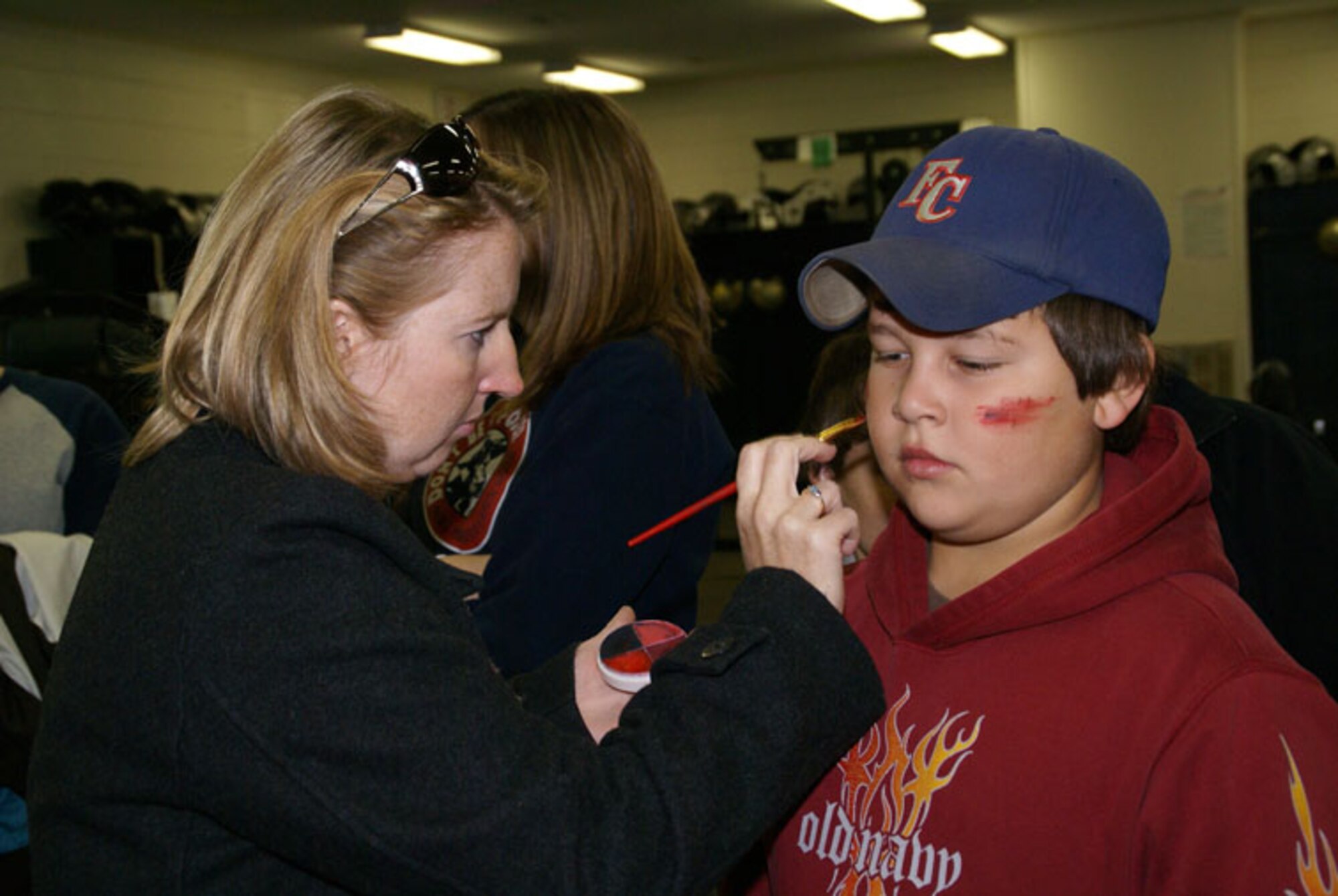 Suzanne Mitchell, Franklin County High School registered nurse, applies moulage paint to Justin Moore, a 6th grader at South Middle School in preparation for a mass casualty training exercise Nov. 10. The young man was one of 12 Boy Scouts from Troop 185 in Winchester who took part, playing the role of “victims.” (Photo by Philip Lorenz III)
