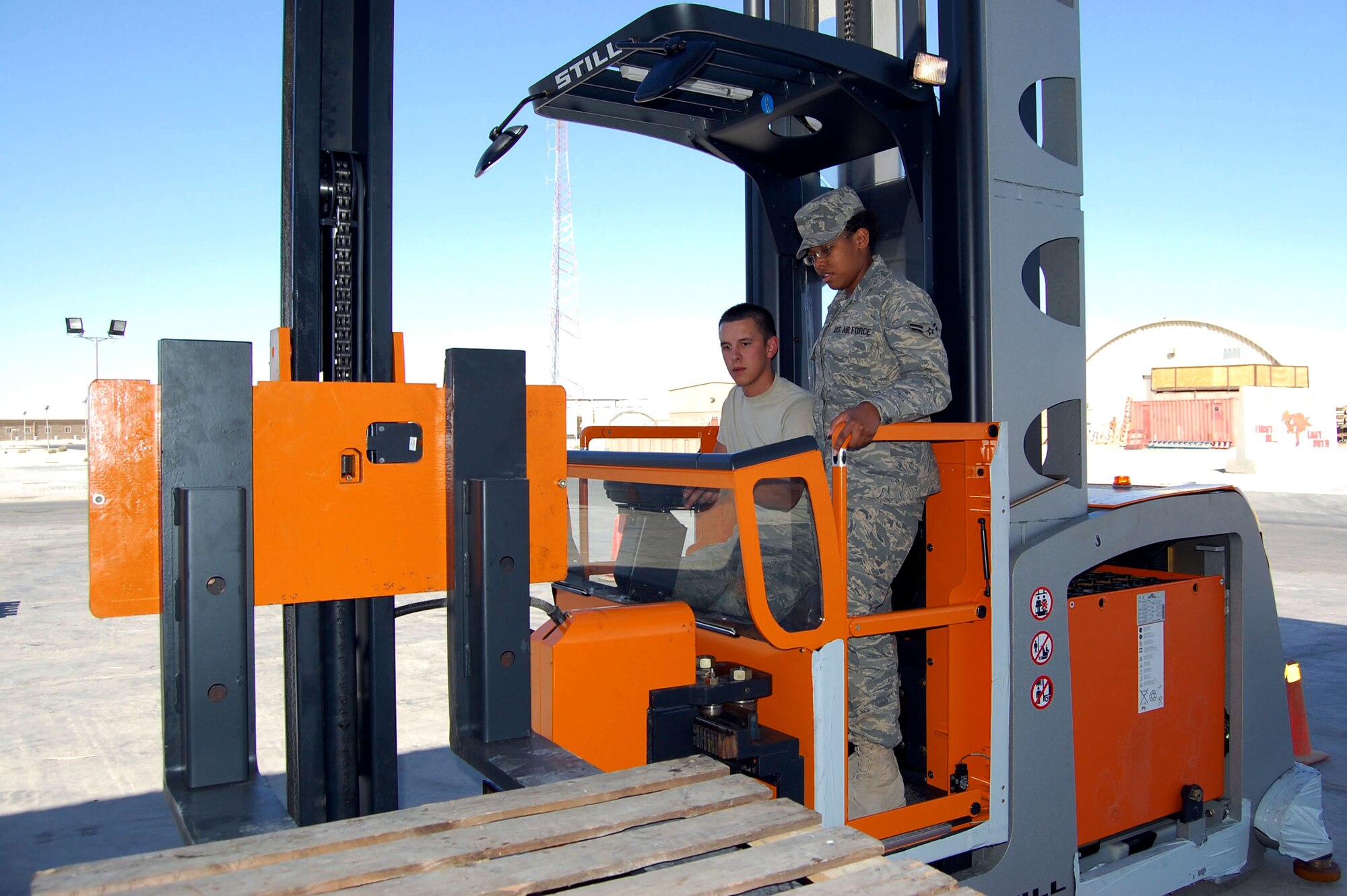 Airman 1st Class Nicholas Guillory teaches Airman 1st Class Charity Carter how to operate the new shelf loading forklift Nov. 7 at the expeditionary theater distribution center in Southwest Asia. Both Airmen are assigned to the 386th Expeditionary Logistics Readiness Squadron and are stationed at Barksdale Air Force Base, La. (U.S. Air Force photo/Staff Sgt. Phillip Butterfield)