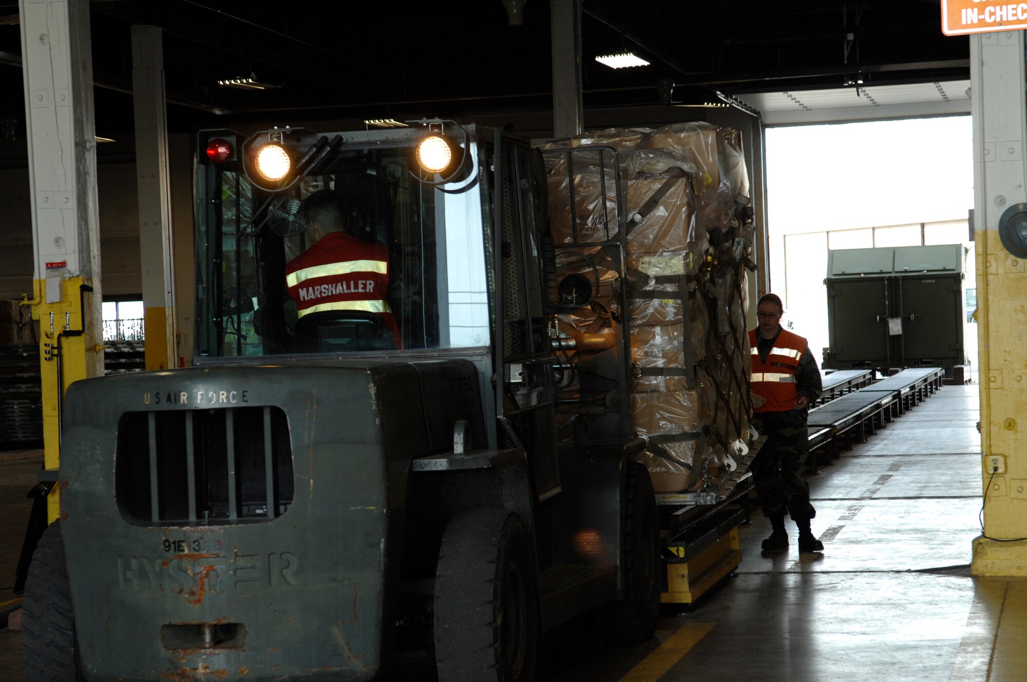 Senior Airman Steven Wachlin, 28th Services Squadron, marshals in cargo while Airman 1st Class Elishia Taubduring, 28th Logistics Readiness Squadron, spots the cargo during an operational readiness inspection at Ellsworth Air Force Base, S.D., Nov. 15, 2007. The cargo deployment function is responsible for ensuring that all cargo is properly documented and secured for transportation. (U.S. Air Force photo/Senior Airman Angela Ruiz)