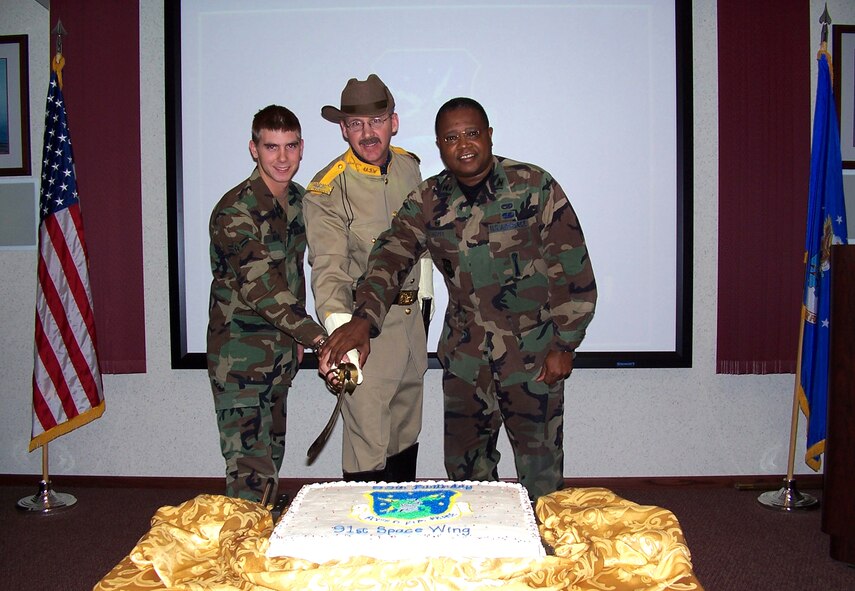 MINOT AIR FORCE BASE, N.D. -- The 91st Space Wing celebrated its 59th
birthday during a cake cutting ceremony Nov. 10. Master Sergeant Dave
Larrison (center) portrayed Teddy Roosevelt, the wing's mascot. Airman 1st
Class Derek Allen (left) was the newest member to the wing and Col. Ray
Scott, 91st Maintenance Group commander, represented one of the wing's
seasoned veterans. (U.S. Air Force photo by Tech. Sgt. Yolanda Williams)