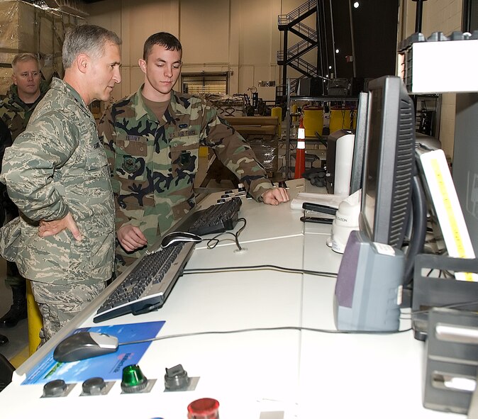 Airman 1st Class Michael Tierney, 436th Aerial Port Squadron (right), describes his shop’s Inventory Control System that is being utilized in the new APS facility to Maj. Gen. James Hawkins, 18th Air Force commander as Lt. Col. Brian Fletcher, 436th APS commander listens. The new, automated ICS saves APS Airmen time and labor. (U.S. Air Force photo/Jason Minto) 
