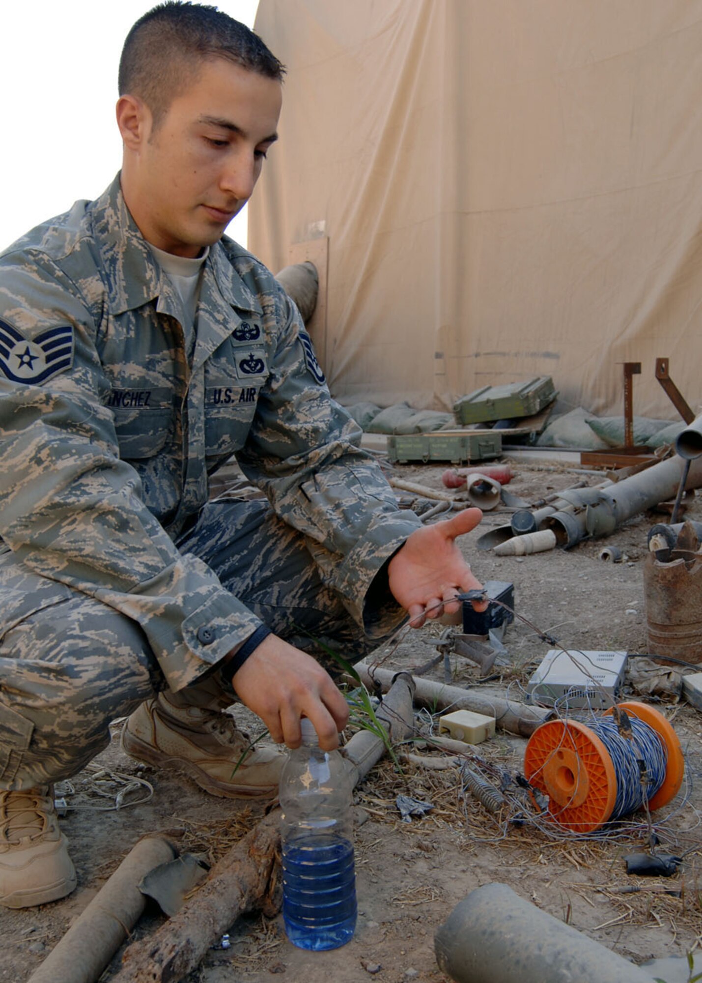 SATHER AIR BASE, Iraq -- Staff Sgt. Carlos Sanchez, 447th Expeditionary Civil Engineer Squadron Explosive Ordnance Disposal technician, shows a pressure wire once planted by insurgents, but now serves as a visual example of improvised explosive device-making materials in the unit’s “IED graveyard.” The wires are wound and bound to complete an electrical circuit with pressure, such as from a foot or a vehicle tire, setting off an explosion designed to maim or kill its victims. Sergeant Sanchez is part of a team of EOD technicians serving at Sather AB, Baghdad, Iraq. He is deployed from Eglin Air Force Base, Fla. (Staff Sgt. Jennifer Lindsey)