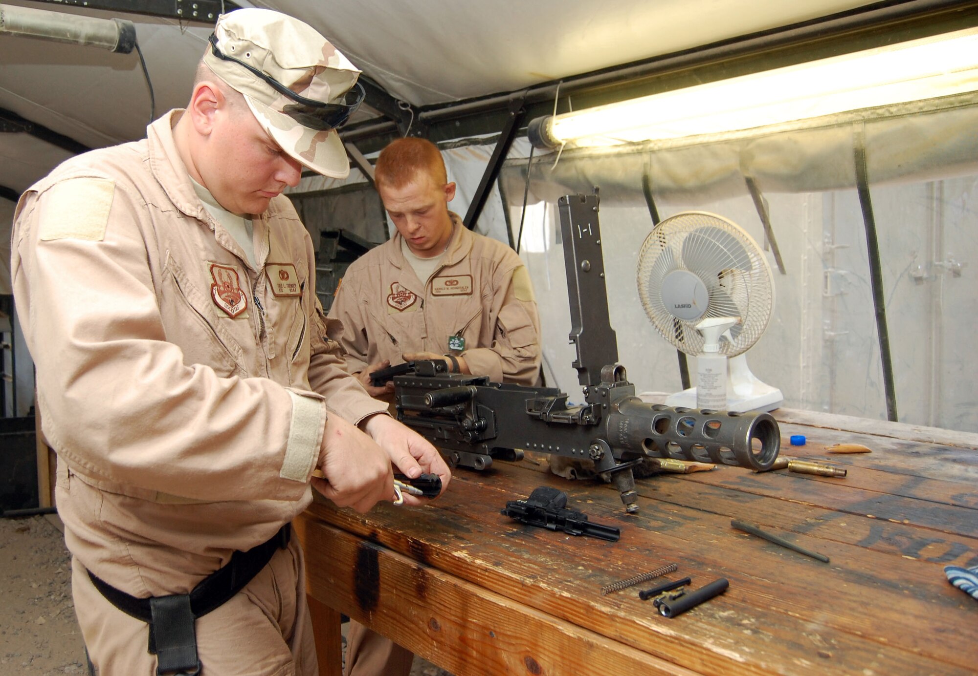 SOUTHWEST ASIA – Airman 1st Class Cole Turner and Senior Airman Harold Houghtalen, 887th Expeditionary Security Forces Cobra Squad fire team members, clean an M-9 pistol and an M-2 heavy machine gun before a mission Nov. 12 at Camp Bucca, Iraq. Airman Houghtalen is from Moody Air Force Base, Ga. and Airman Turner is from Barksdale Air Force Base, La. (Air Force Photo/Staff Sgt. Phillip Butterfield)