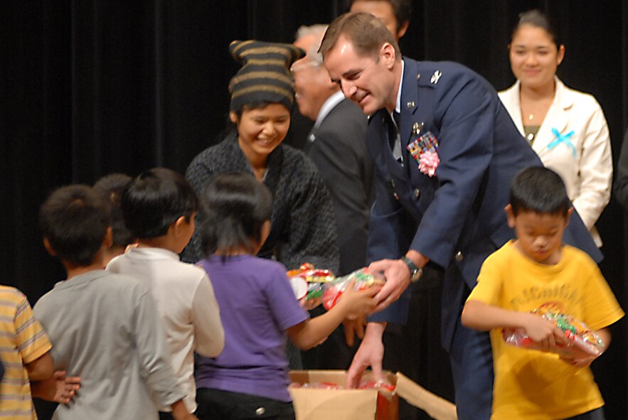 Col. Charles Ennis, 18th Mission Support Group deputy commander, presents gifts to elementary school children for their dance performances of “We love Eisa” and “Tiny Boppers” during Kadena Town's 10th annual English contest Nov. 10. (U.S. Air Force/Airman 1st Class Kasey Zickmund)