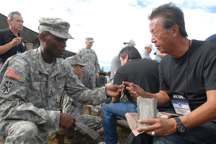 Sgt. 1st Class Robert Dudley, 1-1 Air Defense Artillery Battalion, assists George Namkung with a Meal Ready to Eat during the Joint Civilian Orientation Conference tour Nov. 9, 2007, at Kadena Air Base, Japan. Approximately 40 distinguished visitors took part in this year's conference which included a week-long tour of military forces in the U.S. Pacific Command. JCOC is a Secretary of Defense-sponsored program for expanding America's leader's knowledge of the military and national defense. JCOC is the oldest existing Pentagon outreach program and has been held more than 73 times since 1948. (U.S. photo/Senior Airman Darnell T. Cannady)