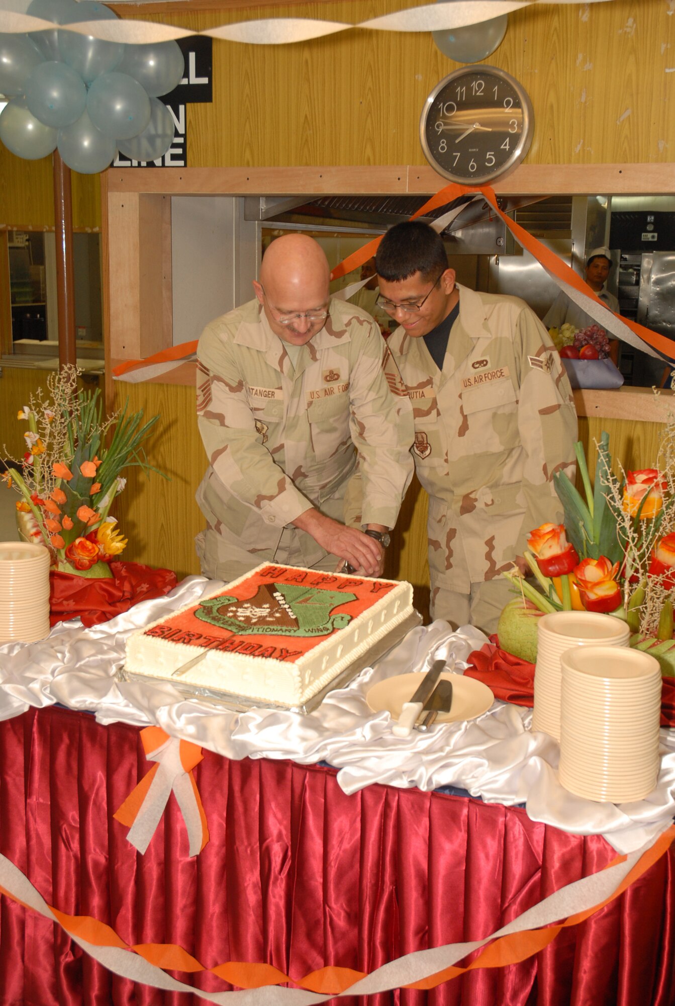 SOUTHWEST ASIA - Senior Master Sgt. Larry Stanger, deployed from the Utah Air National Guard, and Airman 1st Class Mark Urritia, deployed from Dyess AFB, Texas, had the honor of cutting the birthday cake Nov. 13 as the oldest and youngest members celebrating a birthday in the month of November at an air base in Southwest Asia. The birthday dinner is hosted each month, and senior noncommissioned officers and officers serve each member celebrating a birthday that month. (U.S. Air Force photo/Staff Sgt. Douglas Olsen)