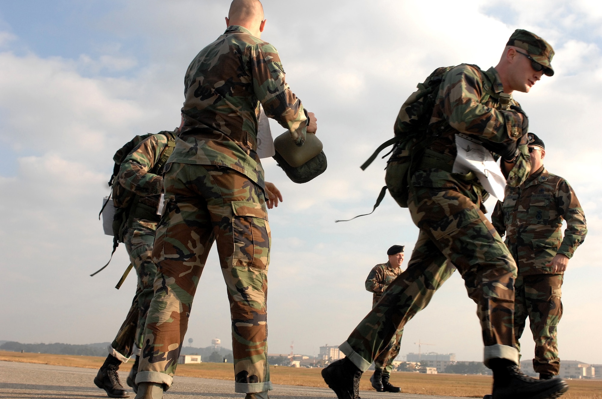 KUNSAN AIR BASE, South Korea  --  Airman Jarves Butler passes canteens to his teammates, 1st Lt. Brett Skates and Senior Airman Dustin Manning during the 1st Annual Veterans Day Memorial Ruck/Run here Nov 17. Skates, Manning and Butler are members of the 8th Security Forces Squadron at Kunsan. Ten teams comprised of four members participated in a 10K march carrying 40 pound ruck sacks followed by a 1.5 mile run. Teams from the Republic of Korea Air Force joined U.S. teams from Kunsan and Osan Air Bases for the competition in an effort to build teamwork and camaraderie.  (U.S. Air Force photo/ TSgt Quinton T. Burris)
