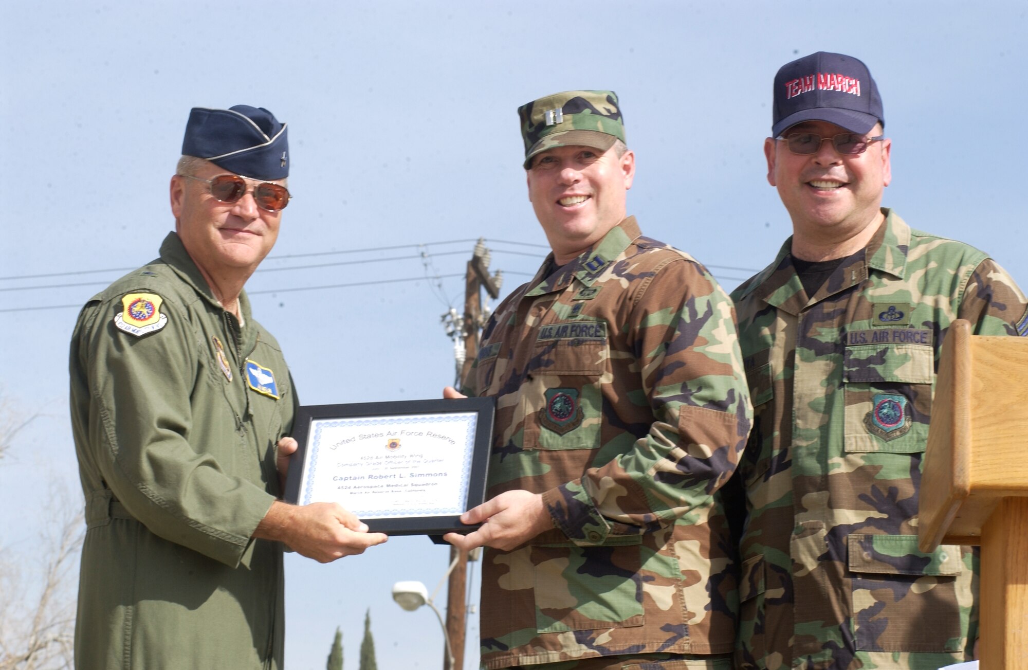 Captain Robert Simmons, center, is recognized as March Air Reserve Base's officer of the quarter.  He is presented the award by Brig. Gen. James Melin, left, commander of the 452nd AMW, and Chief Master Sgt. Agustin Huerta, command chief. The 452nd Air Mobility Wing names its award winners for the fourth quarter of 2007.  The Airman of the quarter was Senior Airman Jaime Maddox from the 452nd Maintenance Operations Squadron.  The NCO of the quarter was Technical Sgt. Diana Perez, 729th Airlift Squadron.  The senior NCO of the quarter was Master Sgt. Javier Padilla from the 452nd Aeromedical Staging Squadron.  The officer of the quarter was Capt. Robert Simmons from the 452nd Aerospace Medicine Squadron.  The civilian of the quarter from GS-1 through GS-6 was Charrice Netters from the 452nd Mission Support Squadron.  The WG category winner was Jason Knapp from 452 Aircraft Maintenance Squadron.  The WS category winner was Berton Perkins from 452 Aircraft Maintenance Squadron.  (U.S. Air Force photo by Staff Sgt. Joe Davidson/ 452 AMW)