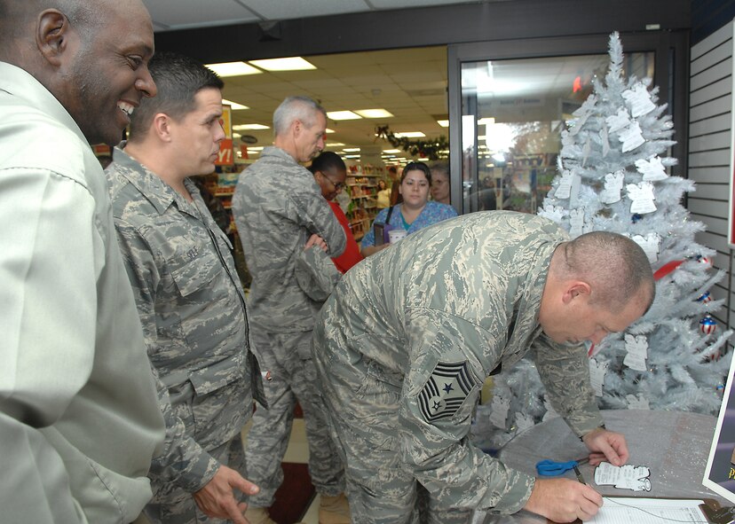 SHAW AIR FORCE BASE, S.C. -- Jonathan Bright, Army Air Force Exchange Service Manager, and Master Sgt. Fred Self, 20th Force Support Squadron first sergeant wait in line as Chief Master Sgt. Scott DearDuff, 20th Fighter Wing command chief, signs his name for the Shaw angel tree Nov. 19. The Shaw angel tree is a base-wide effort sponsored by the chapel to reach out and help those Airmen that have a difficult time during the Christmas holiday to provide gifts for their children.   (U.S. Air Force photo/Airman 1st Class William Coleman)