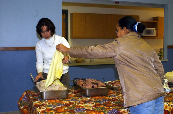 Master Sgt. Janet Alford, 341st Services Squadron first sergeant, and her daughter, Christina, get the turkey ready prior to the start of the Community Thanksgiving dinner Sunday. The event is sponsored by the Catholic and Protestant communities of Malmstrom. (U.S. Air Force photo/Valerie Mullett)