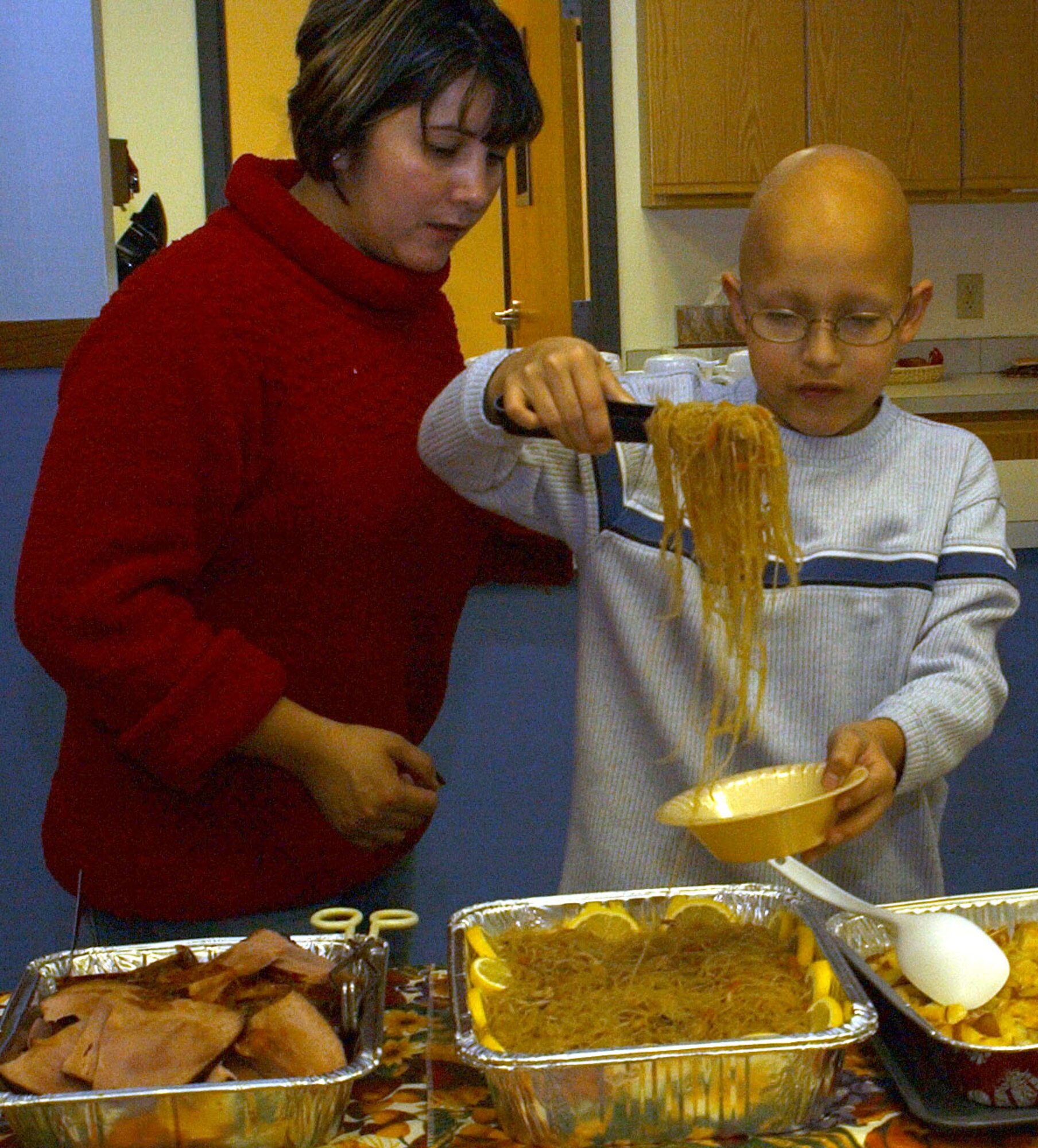 Little Warrior Joey, 11, helps himself to a healthy portion of Lo Mein under the watchful eye of his mom. Members of the Catholic and Protestant communities at Malmstrom came together for a community Thanksgiving dinner at the chapel annex Sunday. (U.S. Air Force photo/Valerie Mullett)