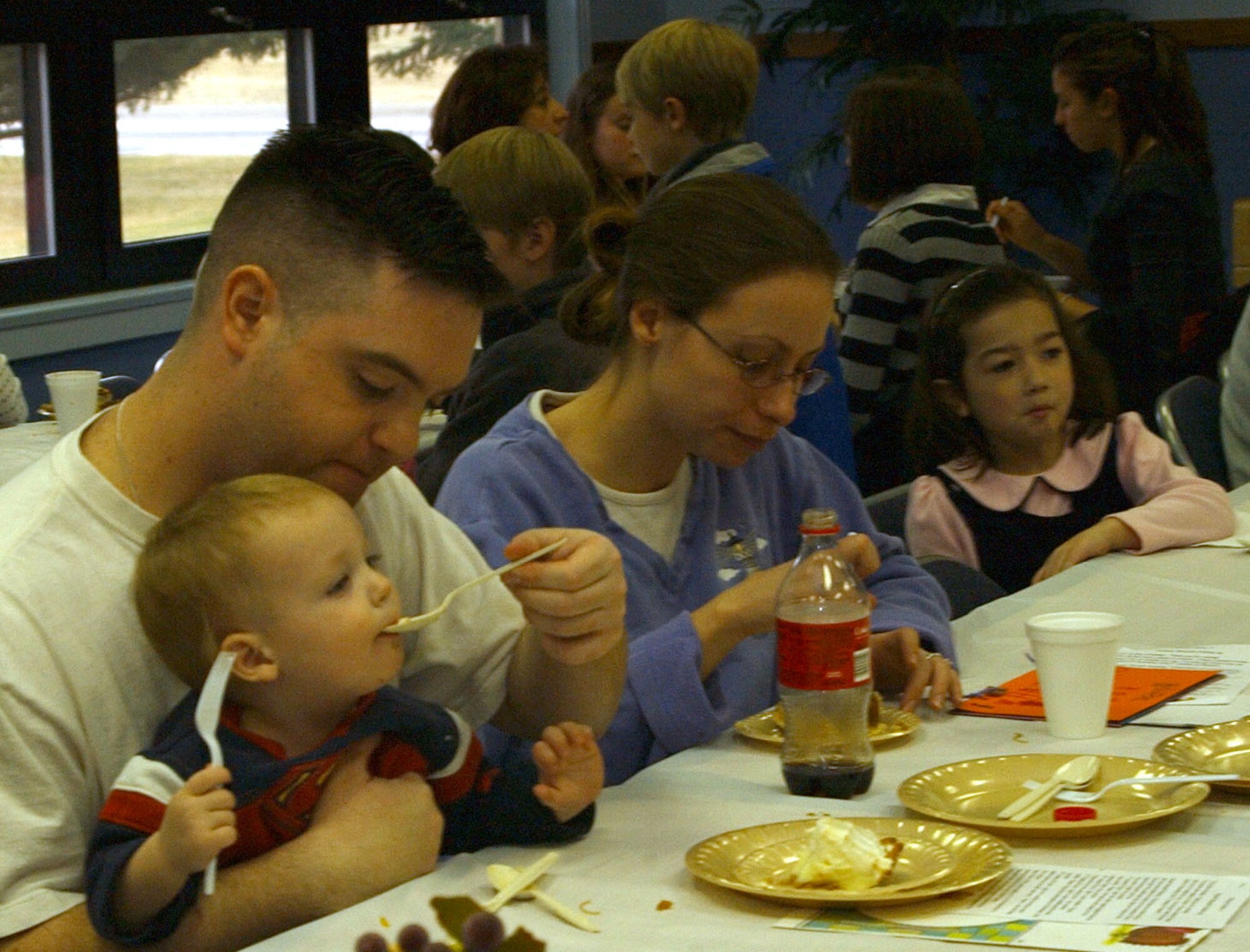 Little Warrior Jacob, 16 months, gets a taste of his dad Jospeh's cream pie at the community Thanksgiving dinner at the Chapel Annex Sunday. The annual holiday event is sponsored by the Catholic and Protestant communities. (U.S. Air Force photo/Valerie Mullett)
