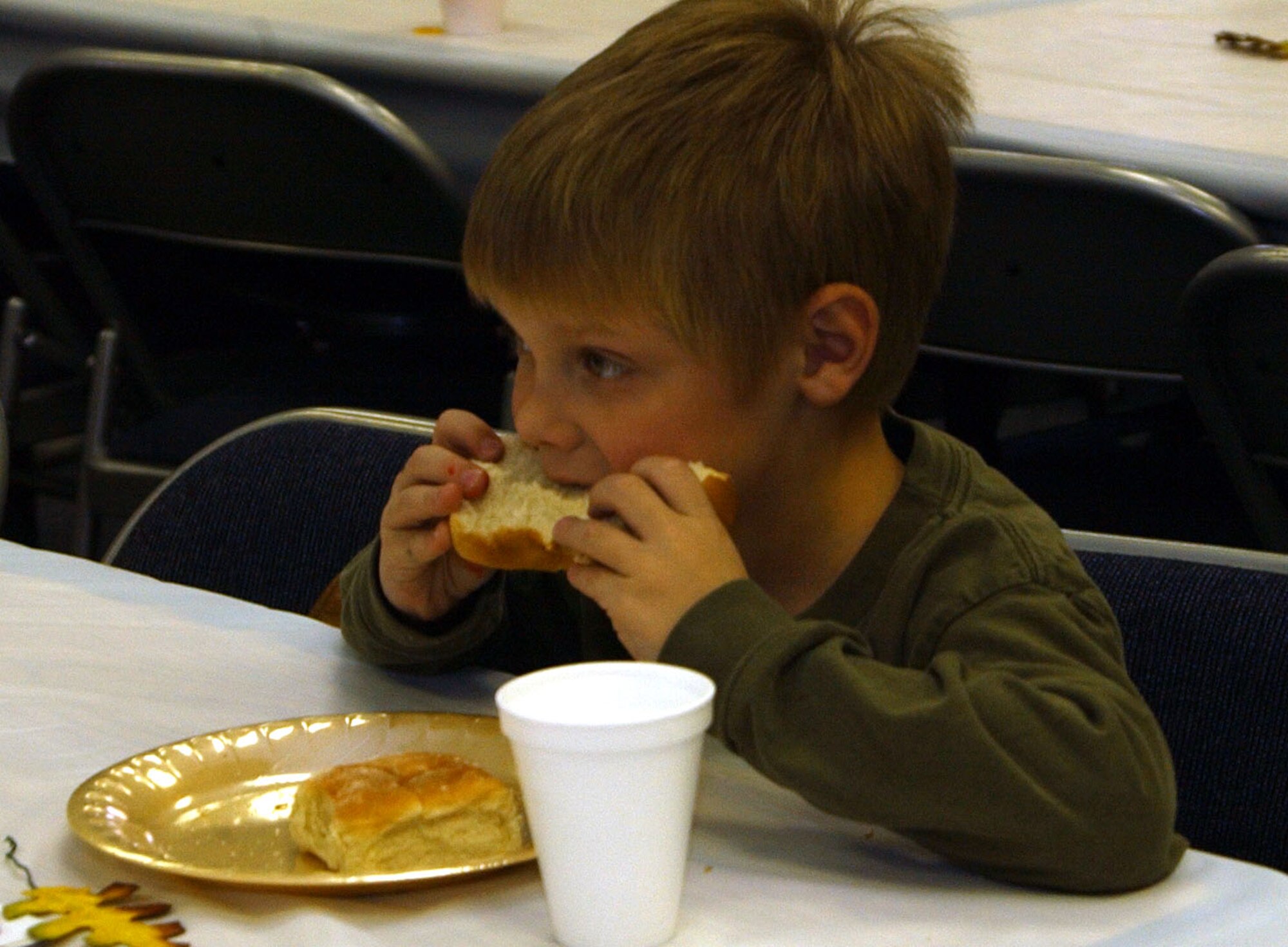 Little Warrior, Joseph, 6, enjoys a dinner roll at the community Thanksgiving dinner at the Chapel Annex Sunday. The annual holiday event is sponsored by the Catholic and Protestant communities. (U.S. Air Force photo/Valerie Mullett)
