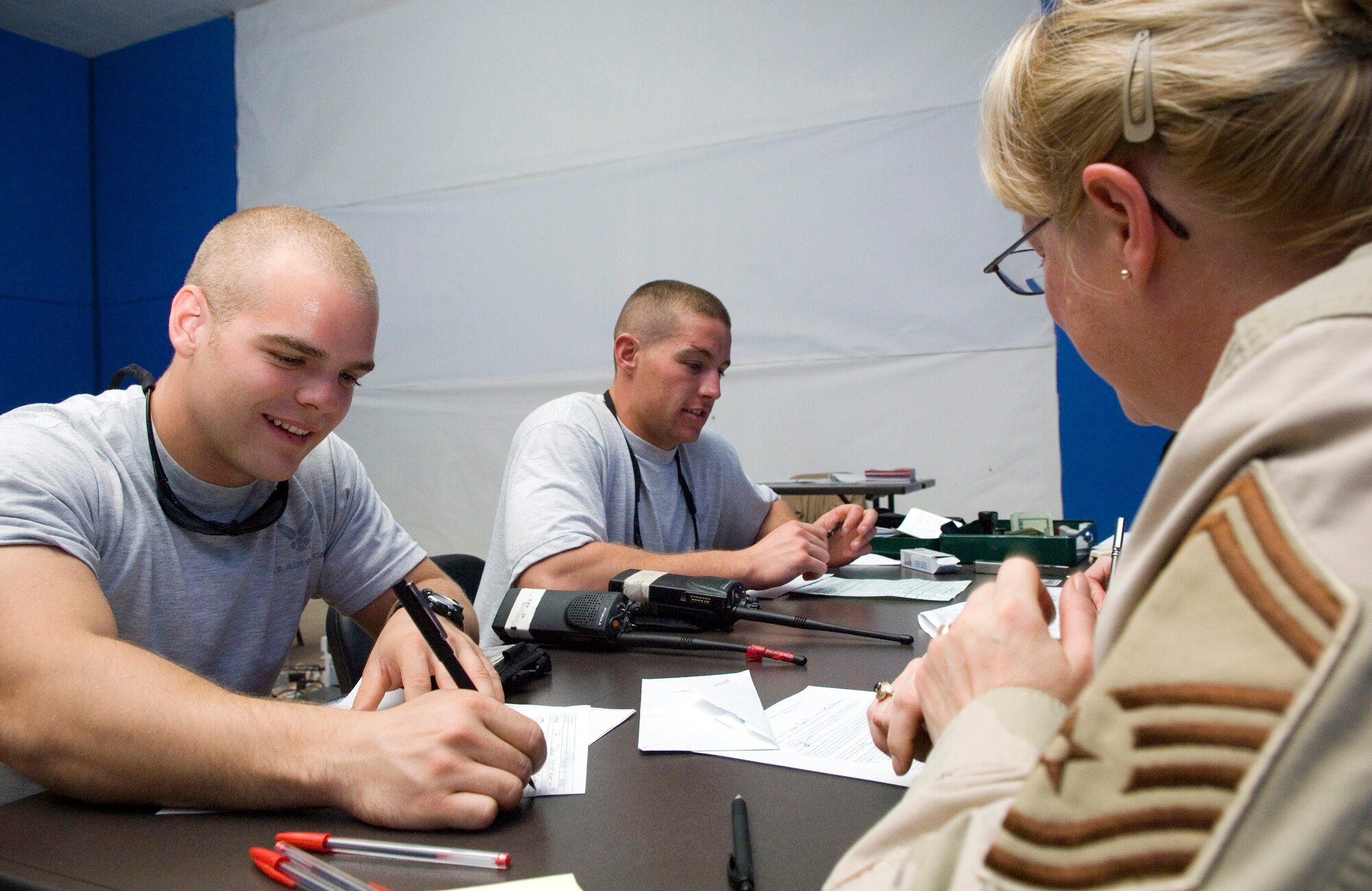 Senior Master Sgt. Veronica Martin reviews paperwork with Airmen 1st Class Richard Jones(center) and Ryan Larson before filing for their first passports. The Airmen took advantage of the U.S. Department of State Foreign Service office visit, which allowed them to file for passports while deployed.  The Airmen are deployed from Aviano Air Base, Italy, and are both assigned to the 332nd Expeditionary Civil Engineer Squadron Fire Department. Sergeant Martin is the 332nd Air Expeditionary Wing Law Office superintendent. (U.S. Air Force photo/Senior Airman Travis Edwards) 