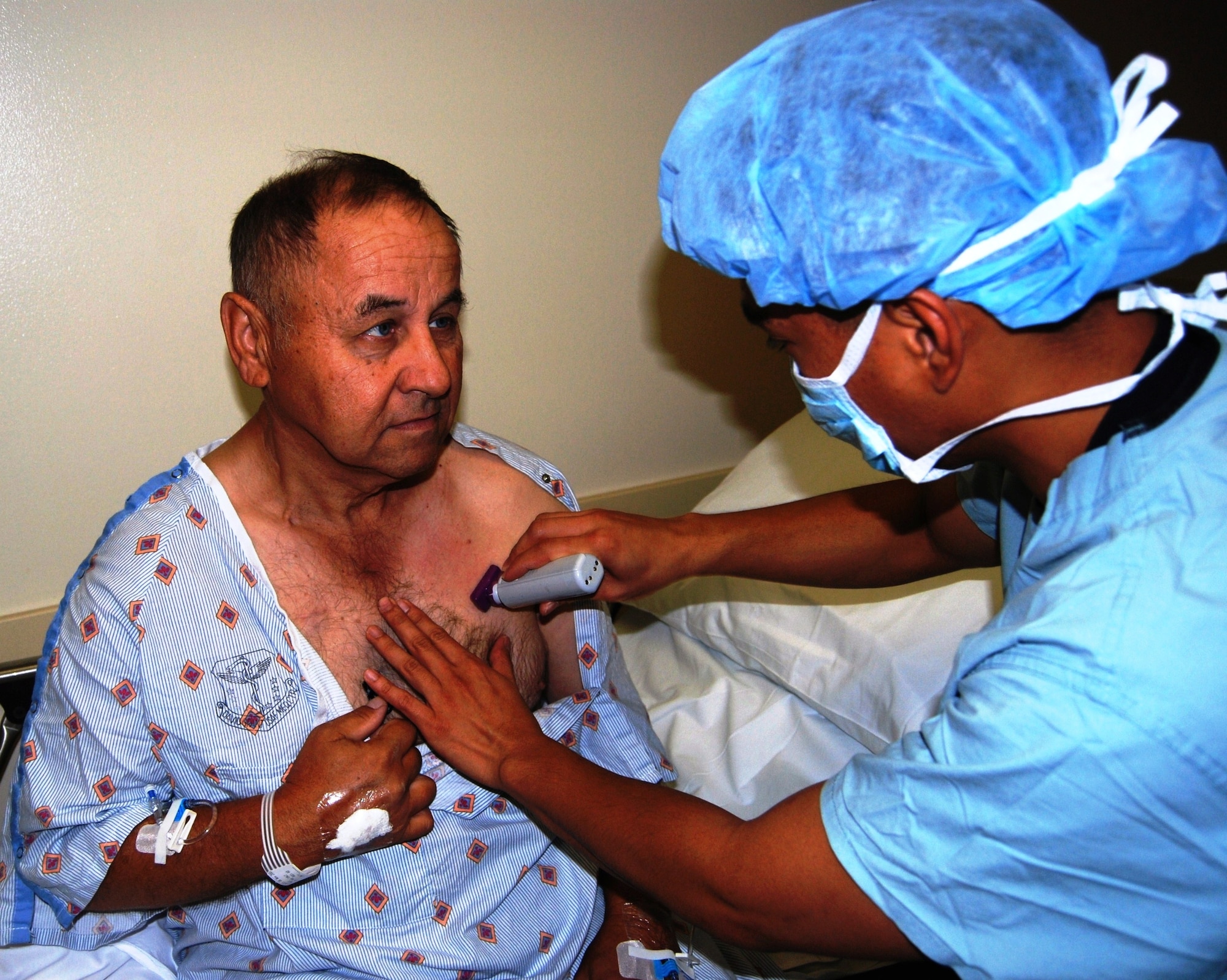 Senior Airman Maynard Galvez, Cardiopulmonary Laboratory technologist, prepares the implantation site of the Current RF Wireless Implantable Cardioverter Defibrillator in Richard Pink’s chest. David Grant USAF Medical Center is the first hospital in the western region to perform the implant. (U.S. Air Force photo/Master Sgt. Austin Delacruz Jr.)
