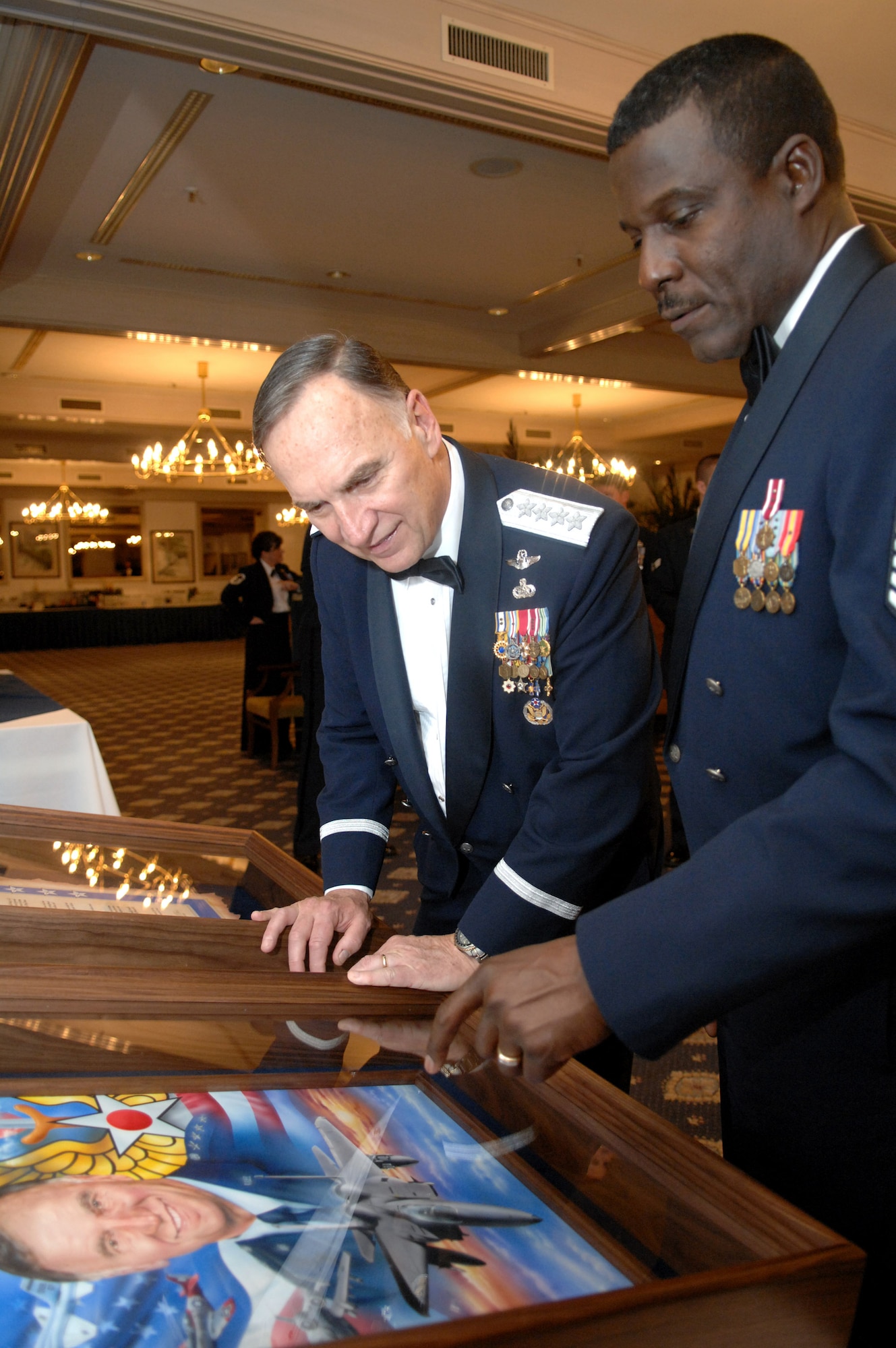 Gen. William T. Hobbins, U.S. Air Forces in Europe commander, admires artwork he received during a USAFE Order of the Sword induction ceremony in his honor. USAFE's top enlisted Airman, Chief Master Sgt. Gary G. Coleman, explains some of the detailing in the work. The Order of the Sword induction is the highest honor the enlisted corps can bestow on an individual. (U.S. Air Force photo/Tech Sgt. Corey Clements) 