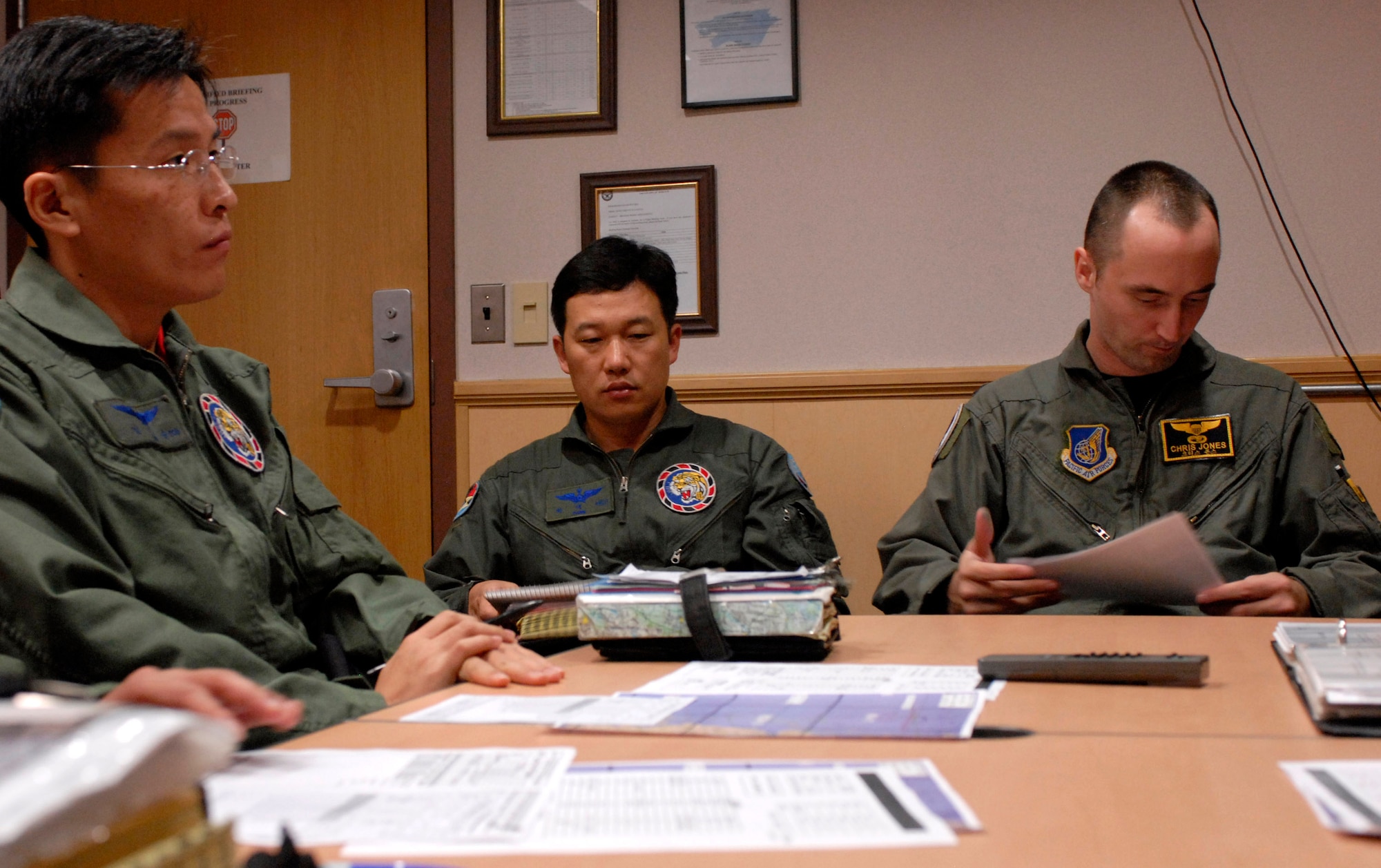 Capt. Yim Chang-soon, weapons officer and Maj. Park Dae-seo, director of operations from the 111th Fighter Squadron and Capt. Christopher Jones, 80th Fighter Squadron pilot, prepare for a flight mission brief here Nov. 14. ROKAF pilots and Wolf Pack pilots trained together on a joint mission to give pilots from both countries a chance to work together and hone their warfighting skills. (U.S. Air Force photo/Staff Sgt. Araceli Alarcon) 