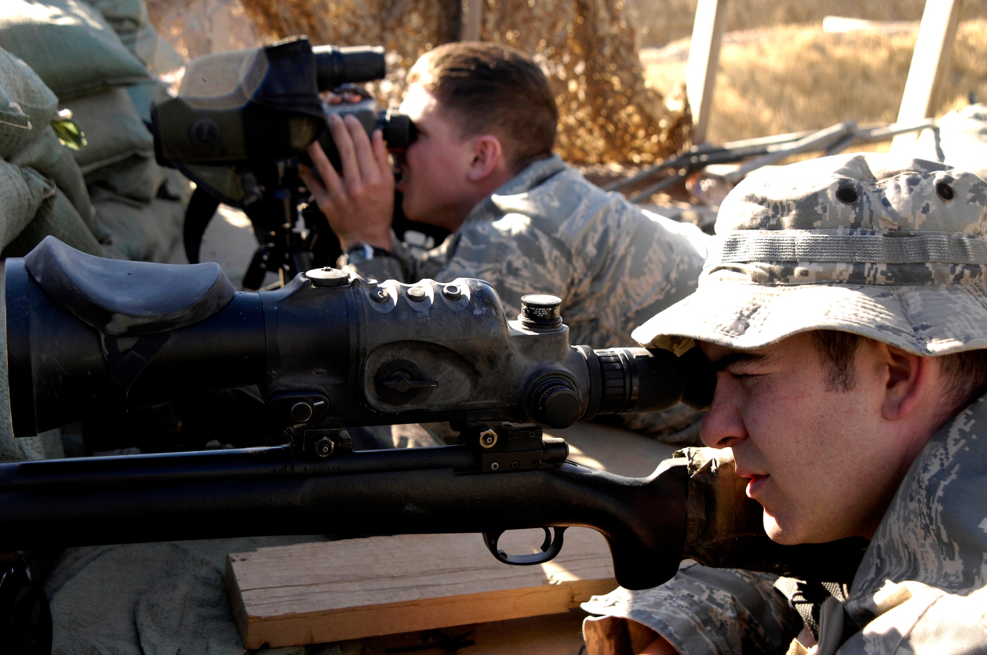 Staff Sgt. Curtis Huffman (background) and Airman 1st Class Matt Leeper set up surveillance on top of a lookout point Nov.13 near Kirkuk Air Base, Iraq. The Airmen are with the 506th Expeditionary Security Forces Squadron Close Precision Engagement team. The CPET members train as anti-sniper teams to target terrorist and insurgent snipers attacking U.S. and coalition forces in the area.The Airmen are deployed from the 354th Security Forces Squadron at Eielson Air Force Base, Alaska. (U.S. Air Force photo/Staff Sgt Angelique Perez) 