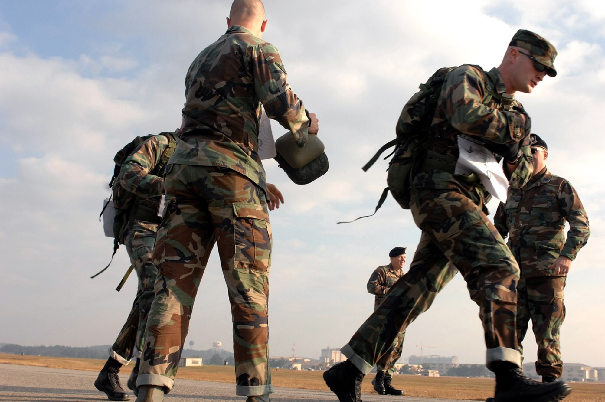 Airman Jarves Butler passes canteens to his teammates, 1st Lt. Brett Skates and Senior Airman Dustin Manning, during the first Veterans Day Memorial Ruck/Run held Nov 17 at Kunsan Air Base, Republic of Korea. The Airmen are members of the 8th Security Forces Squadron. Ten teams, each comprising four members, participated in a 10K march carrying 40 pound ruck sacks followed by a 1.5 mile run. Teams from the Republic of Korea air force joined U.S. teams from Kunsan and Osan air bases for the competition in an effort to build teamwork and camaraderie. (U.S. Air Force photo/Tech. Sgt. Quinton T. Burris)