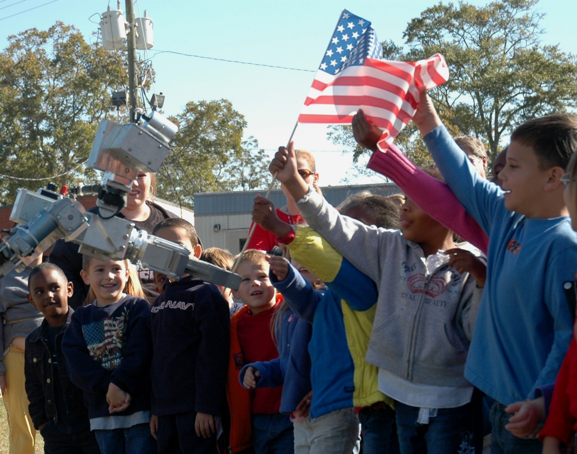 Demonstrating the versatility of the HD-1 robot, Tech. Sgt. Peter McNally maneuvers the robot and presents the American Flag to KMS Elementary students. (U.S. Air Force Photo By/Staff Sgt. Vesta Anderson)