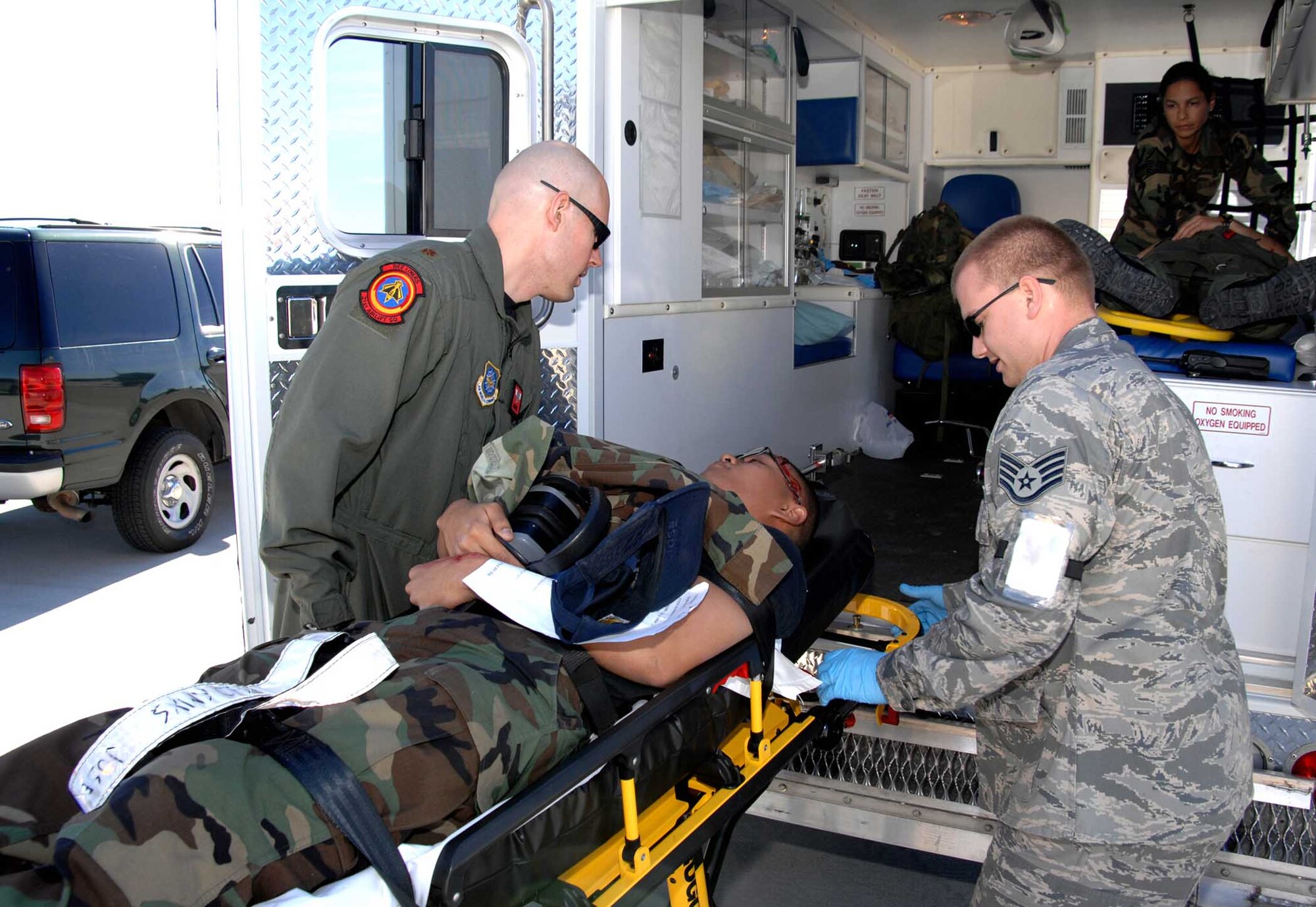 Maj. Christopher Bird, (left), 60th Aerospace Medicine Squadron flight surgeon and Staff Sgt. Mathias Blitz, lift Airman 1st Class Emmanuel Jose, 860th Aircraft Maintenance Squadron into an ambulance for treatment. The simulation was part of the Home Station Attack Response Exercise that tested the capabilities of Team Travis and the Solano County community in the event of an attack. (U.S. Air Force photo)