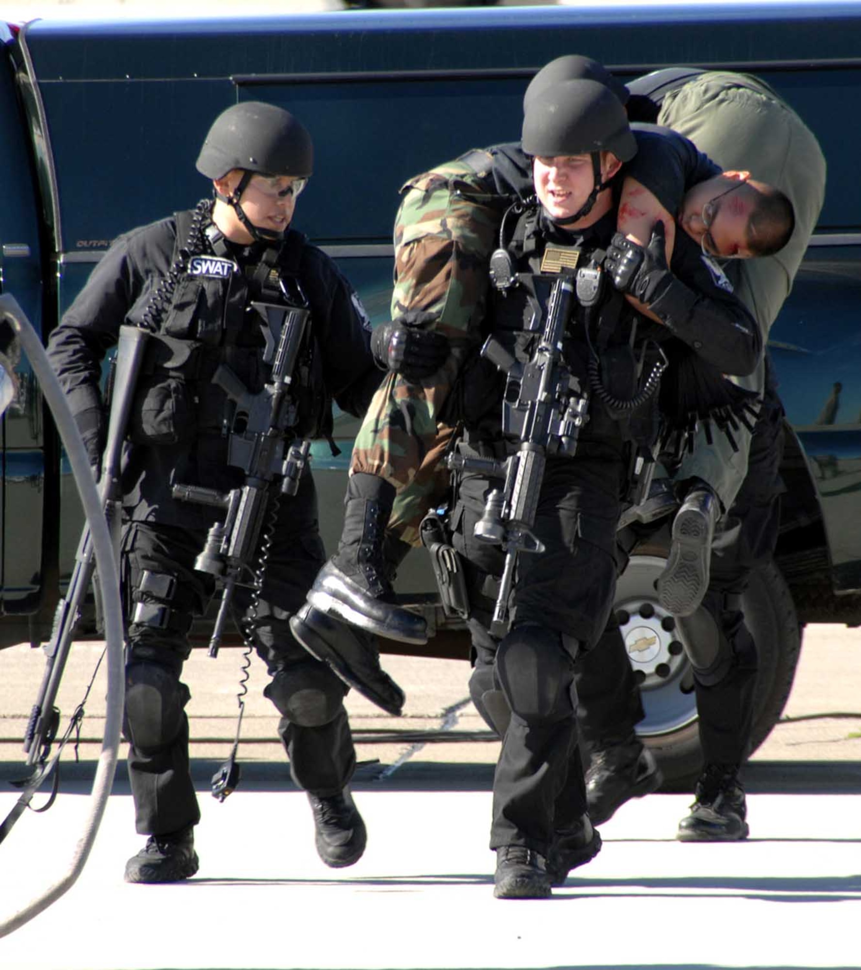 Staff Sgt. David Lopez, SWAT team leader (left) assists Staff Sgt. William McCoy, SWAT team member, carry Airman 1st Class Emmanuel Jose, 860th Aircraft Maintenance Squadron, from the scene of the attempted hi-jacking. The incident was part of the Home Station Attack Response Exercise that tested the abilities of servicemembers and the capabilities of Travis and the Solano County community in the event of an attack. (U.S. Air Force photo)