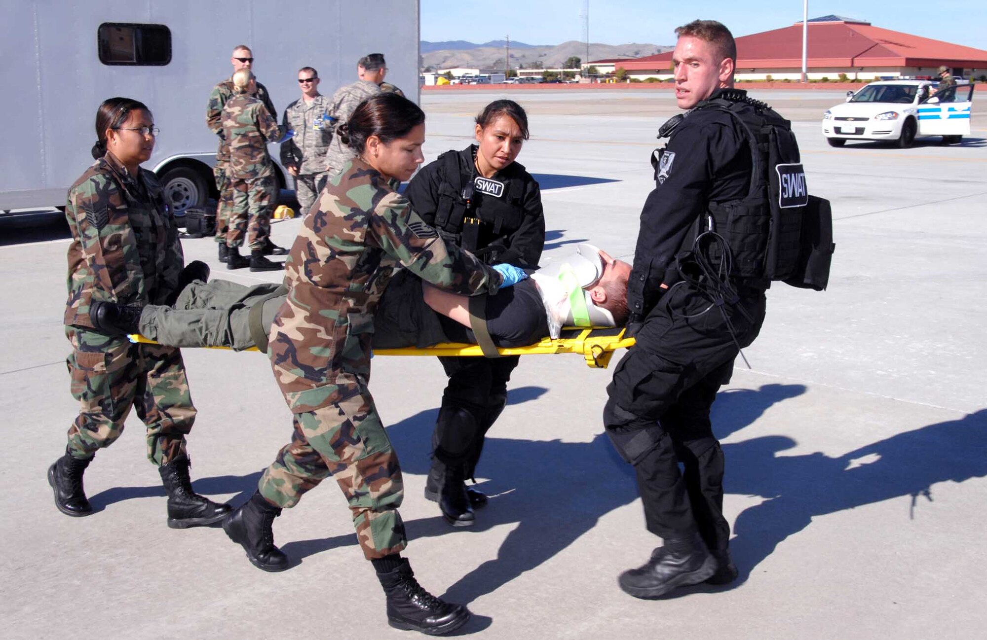 SWAT team members Staff Sgt. Sherry Brown (second from right) and Staff Sgt. William Kelly (far right) assist 60th Aerospace Medicine Squadron flight medicine personnel Master Sgt. Abigail Rivera (2nd from left), and Tech. Sgt. Kristine Valeros (far left) carry simulated gunshot victim Airman 1st Class Kyle Curry, 21st Airlift Squadron to an awaiting ambulance. The simulation was part of the Home Station Attack Response Exercise Nov. 14. (U.S. Air Force photo)